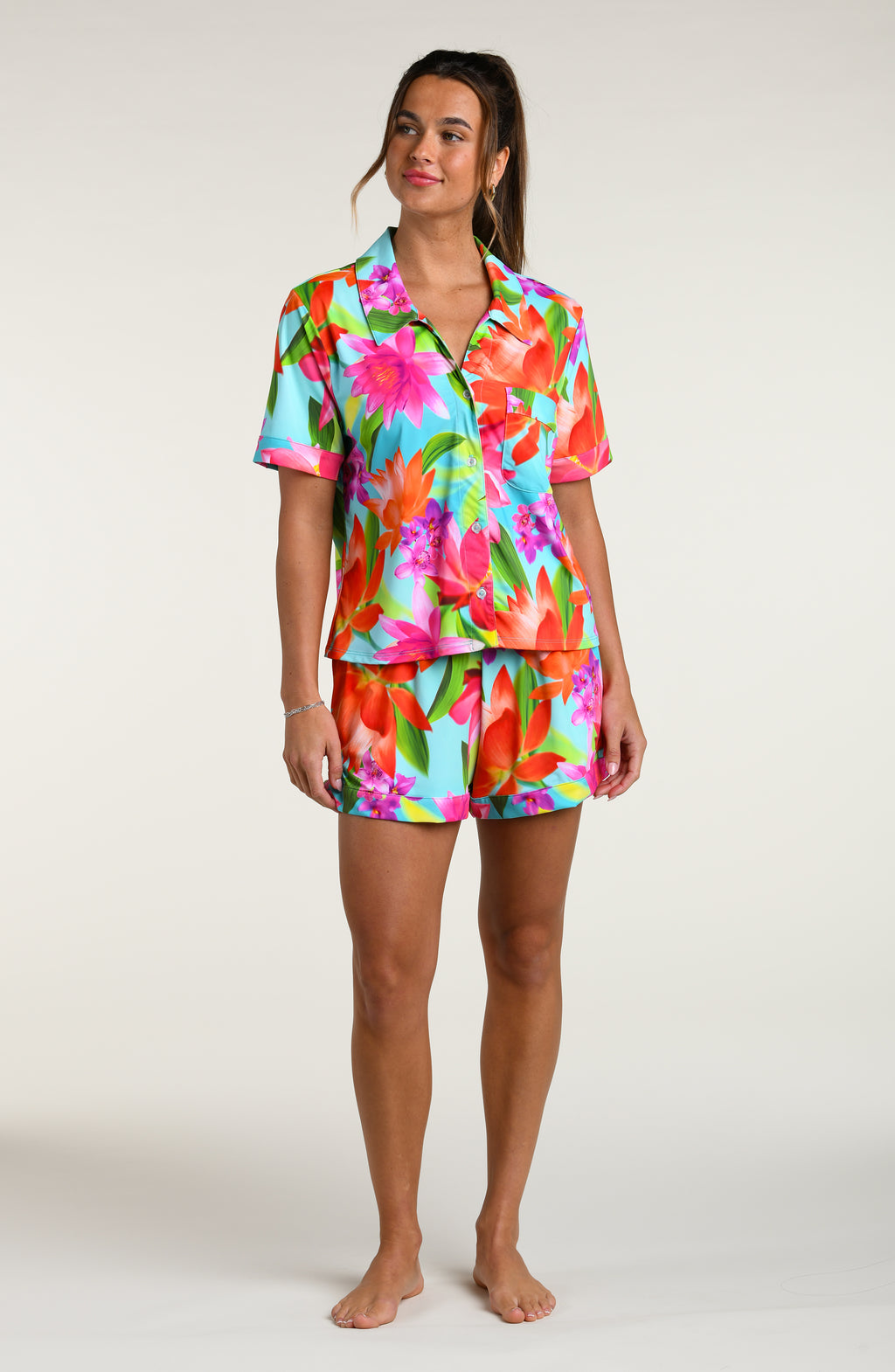 Woman wearing a colorful floral pajama set against a white background