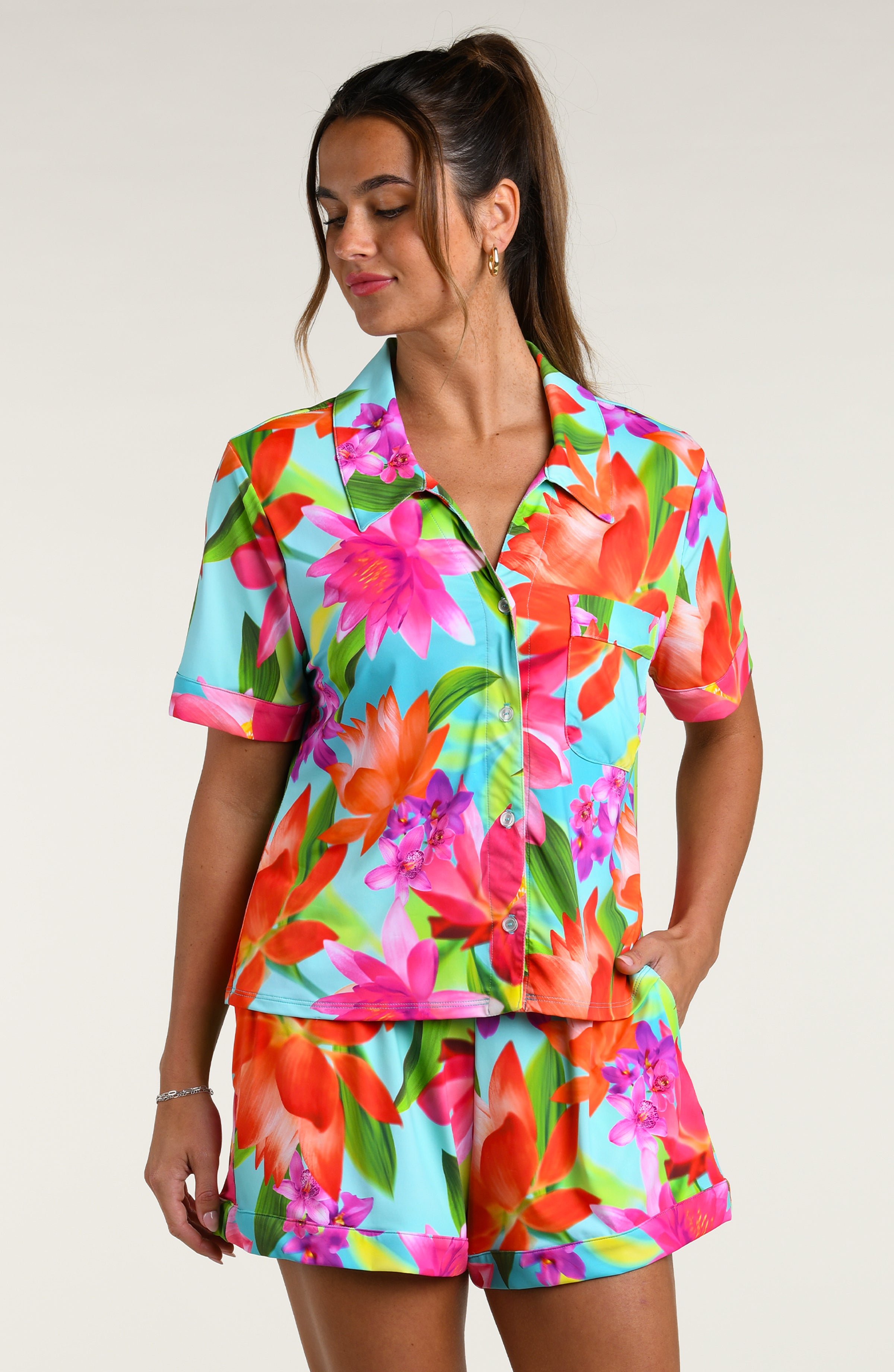 Woman wearing a colorful floral pajama set against a white background