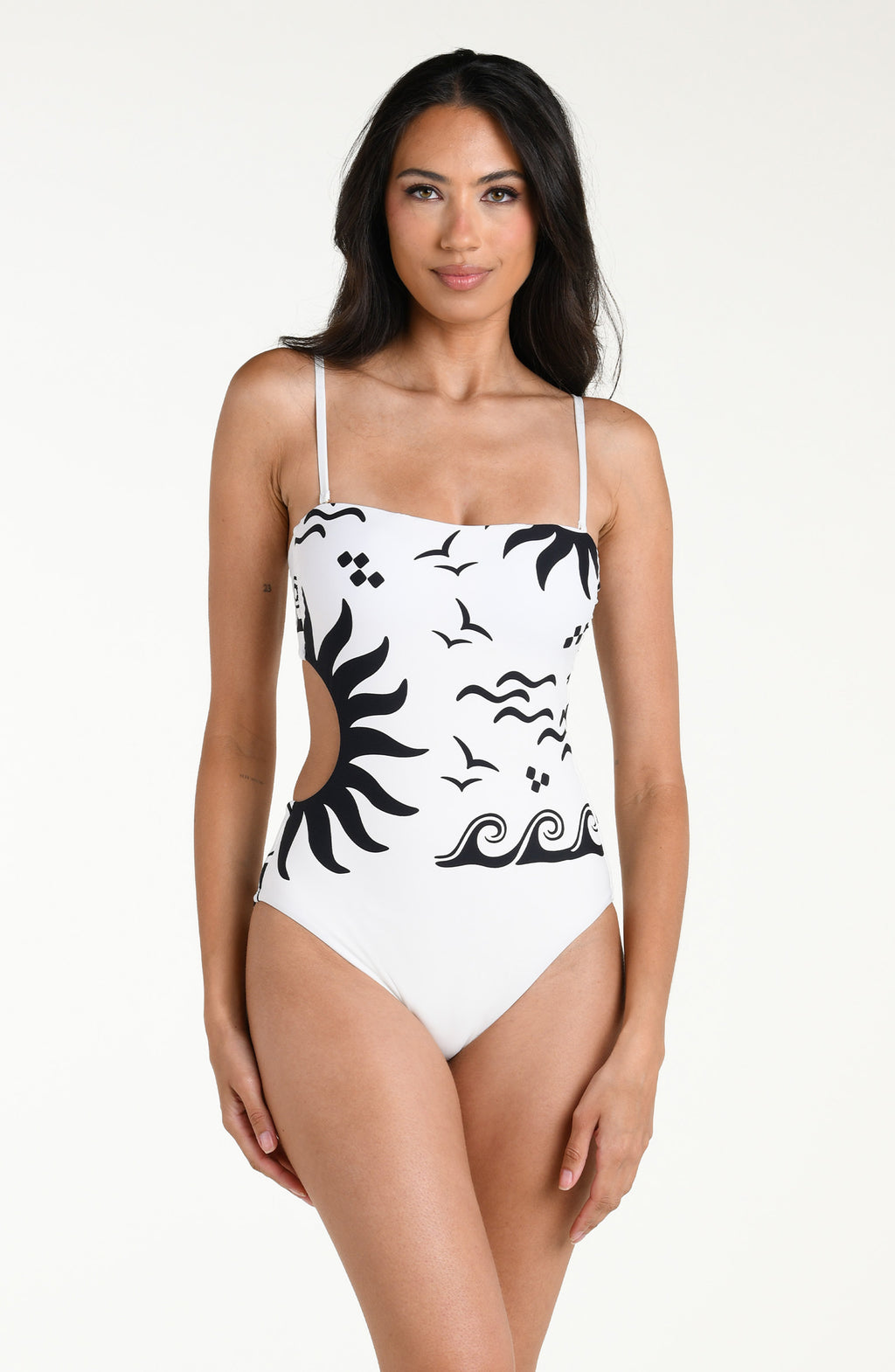 Woman wearing a white one piece swimsuit with black designs on a white background. 