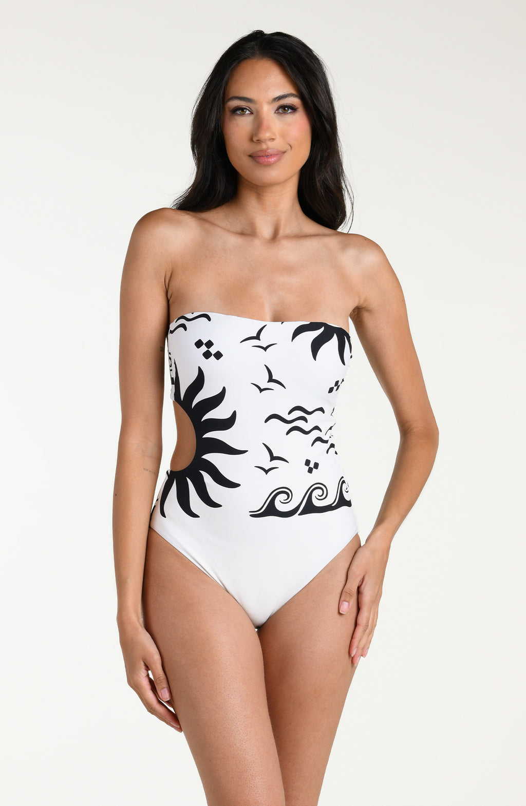 Woman wearing a white one piece swimsuit with black designs on a white background. 