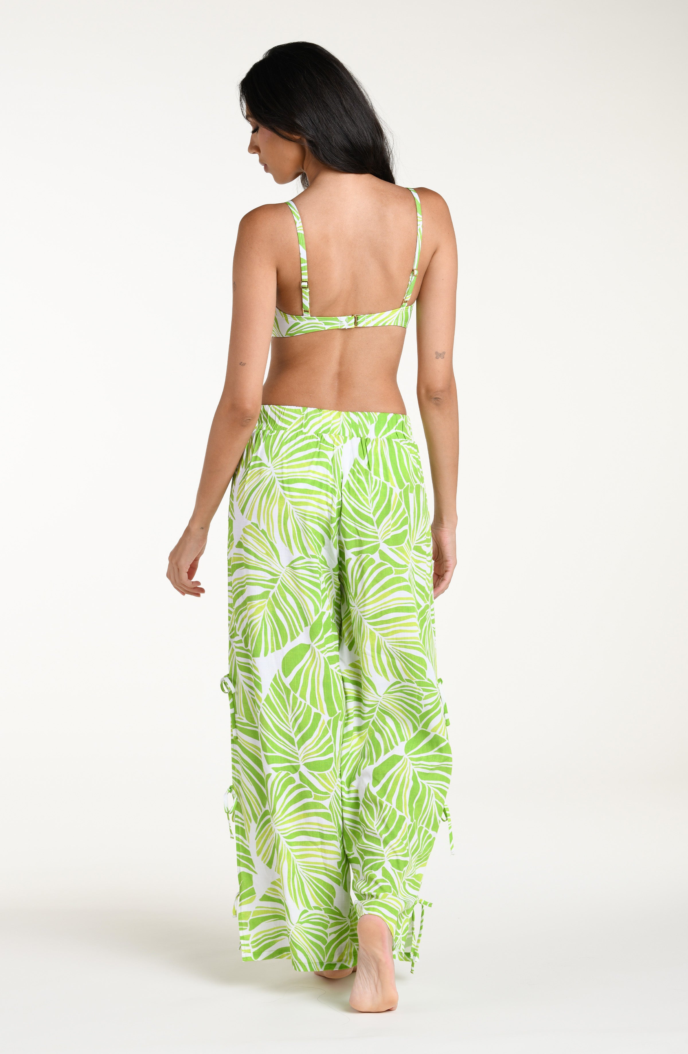 Woman wearing a green and white leaf-patterned beach pants against a white background