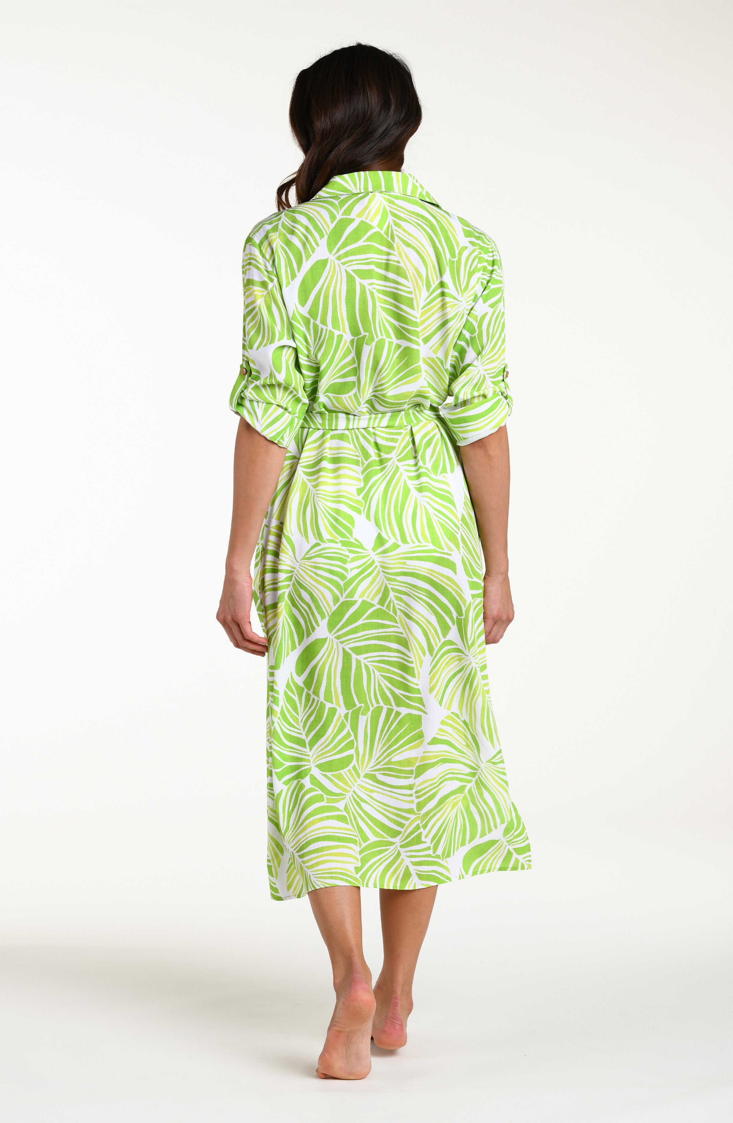 Woman is wearing a green and white leaf-patterned midi dress against a white background