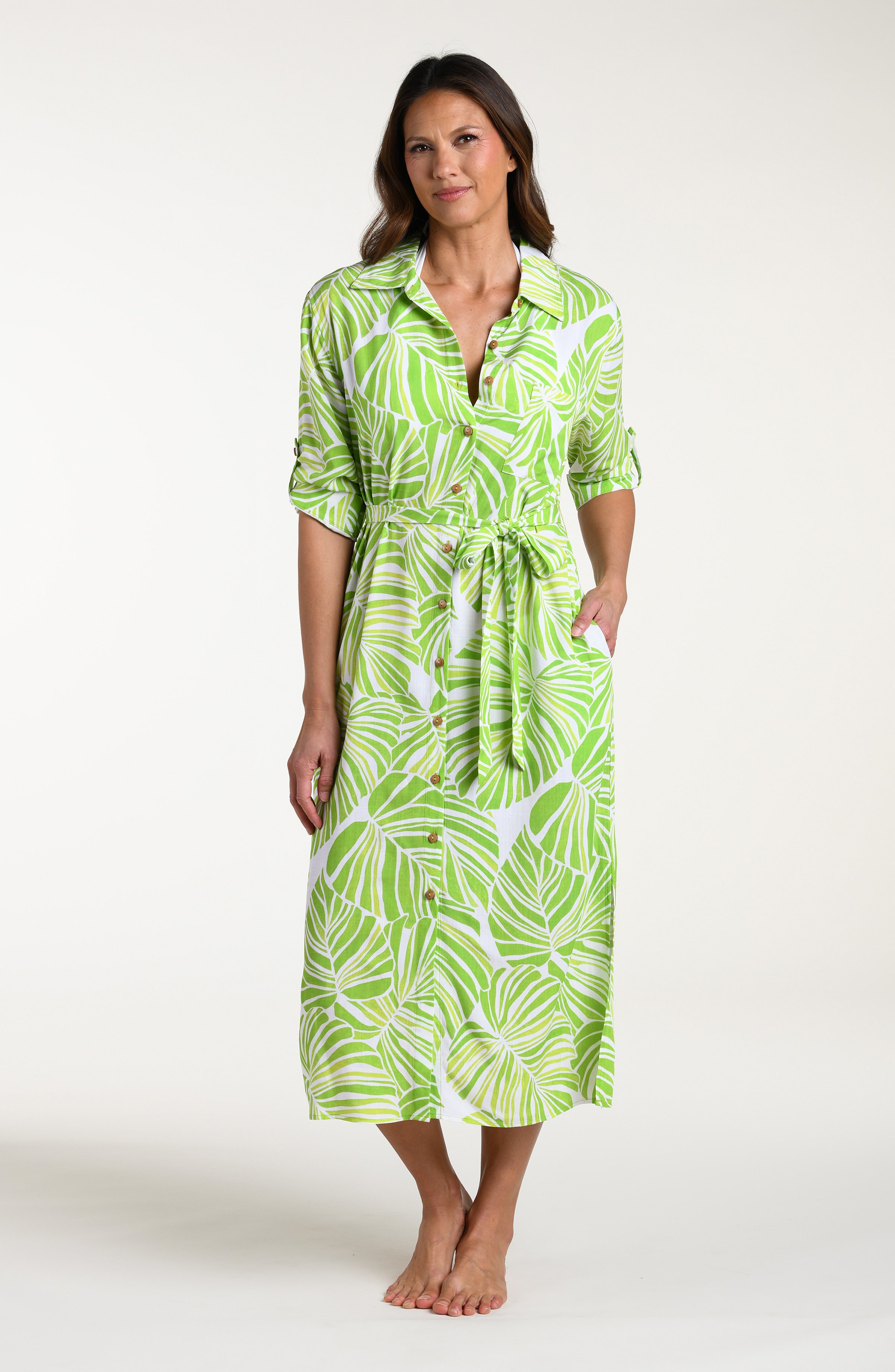 Woman is wearing a green and white leaf-patterned midi dress against a white background