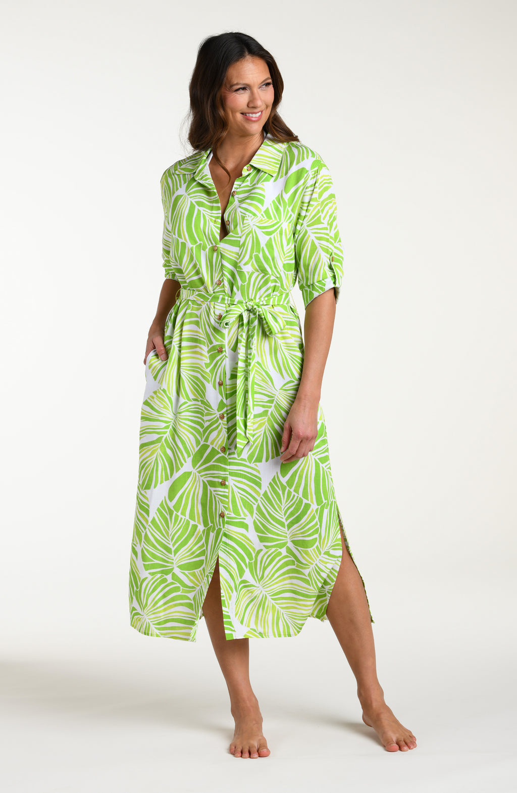 Woman is wearing a green and white leaf-patterned midi dress against a white background