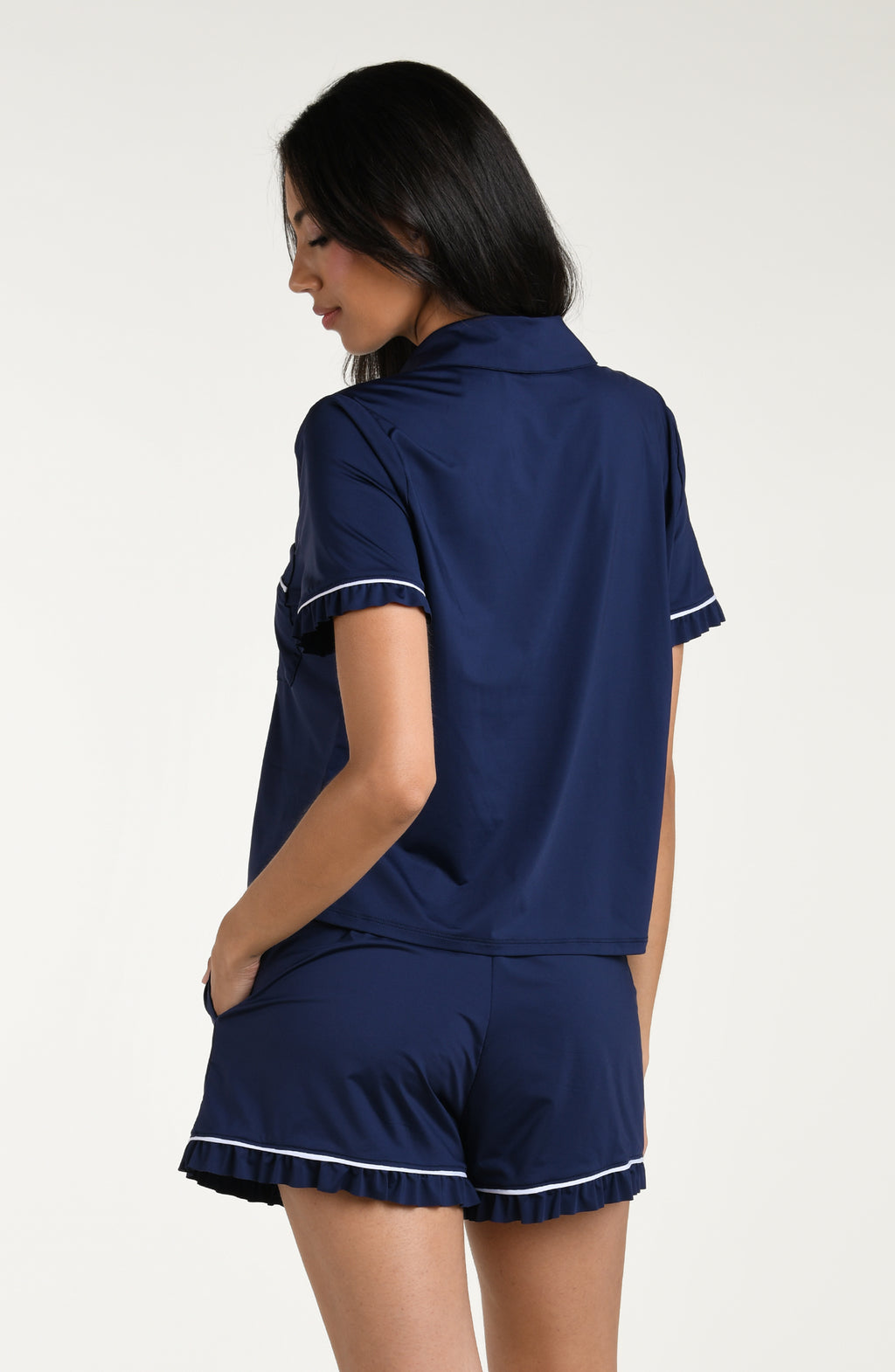 Woman wearing a navy blue pajama set with white trim on a white background