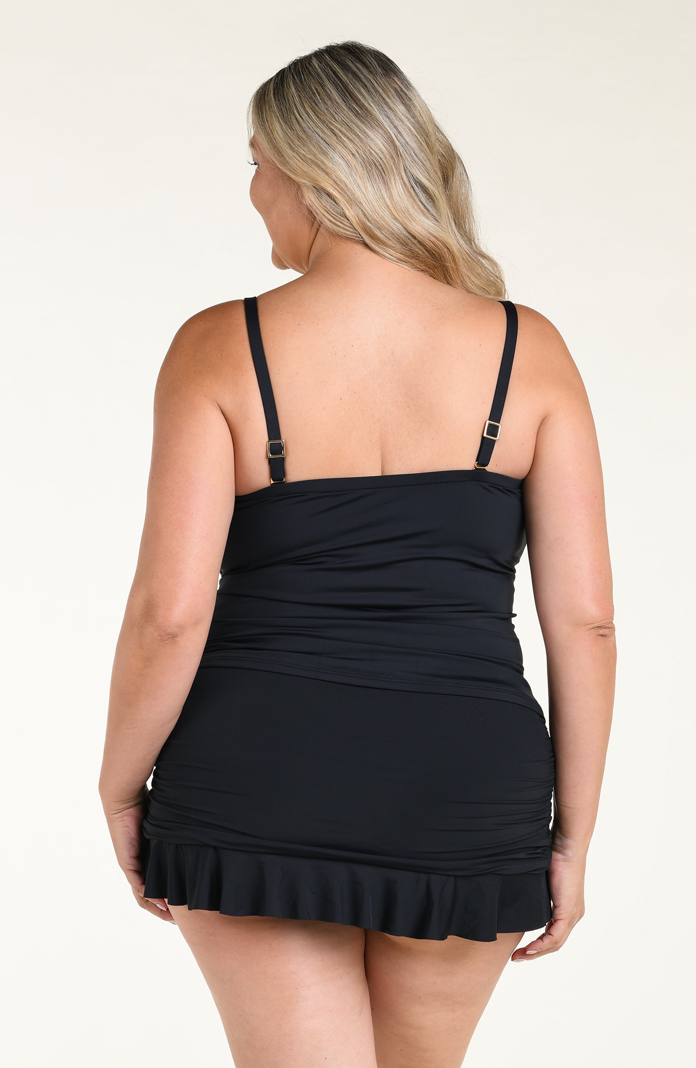 Woman wearing a black ruffled tankini top and matching swim skirt on a white background
