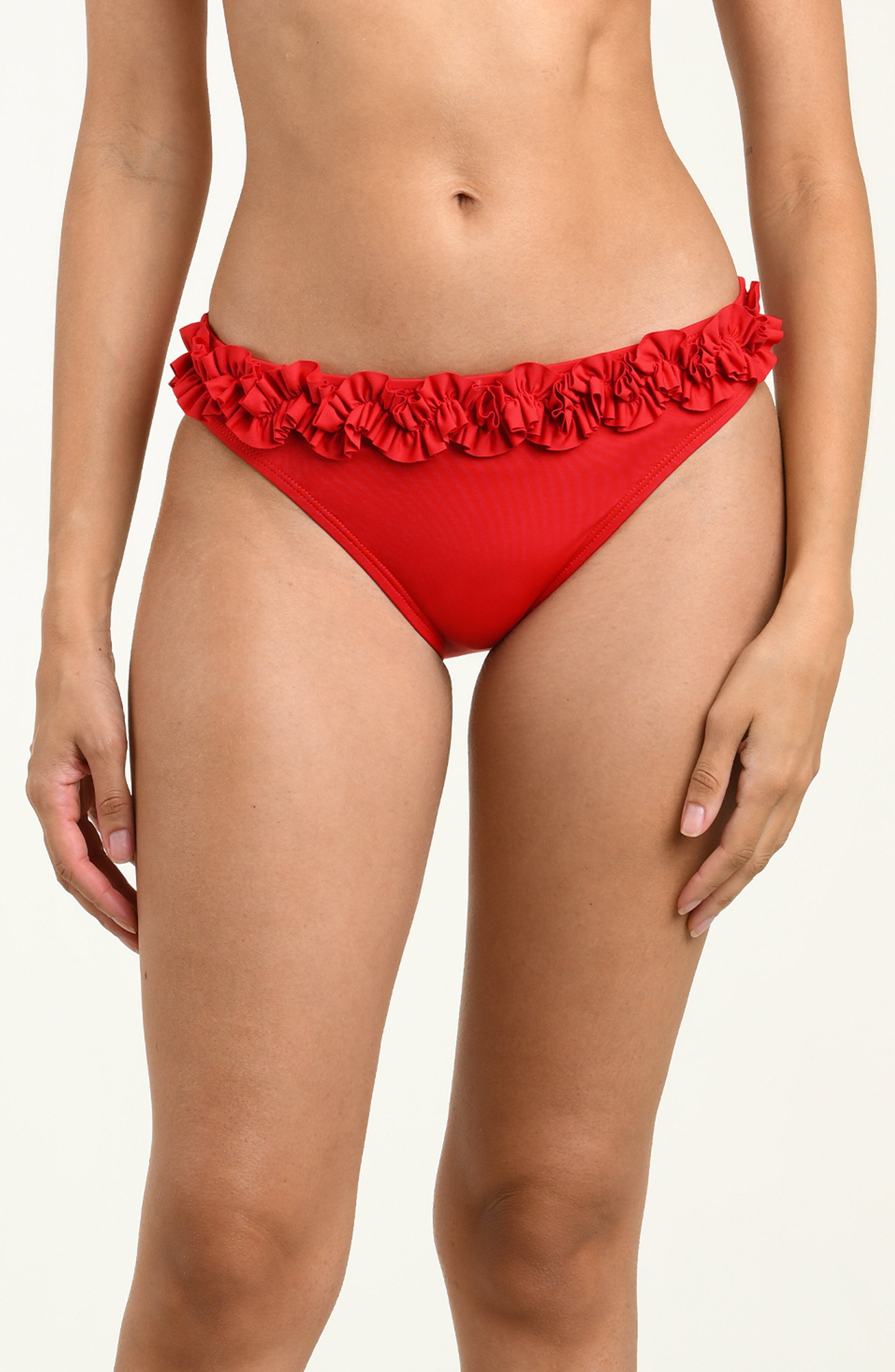 Woman wearing a red bikini bottom with ruffled details on a neutral background