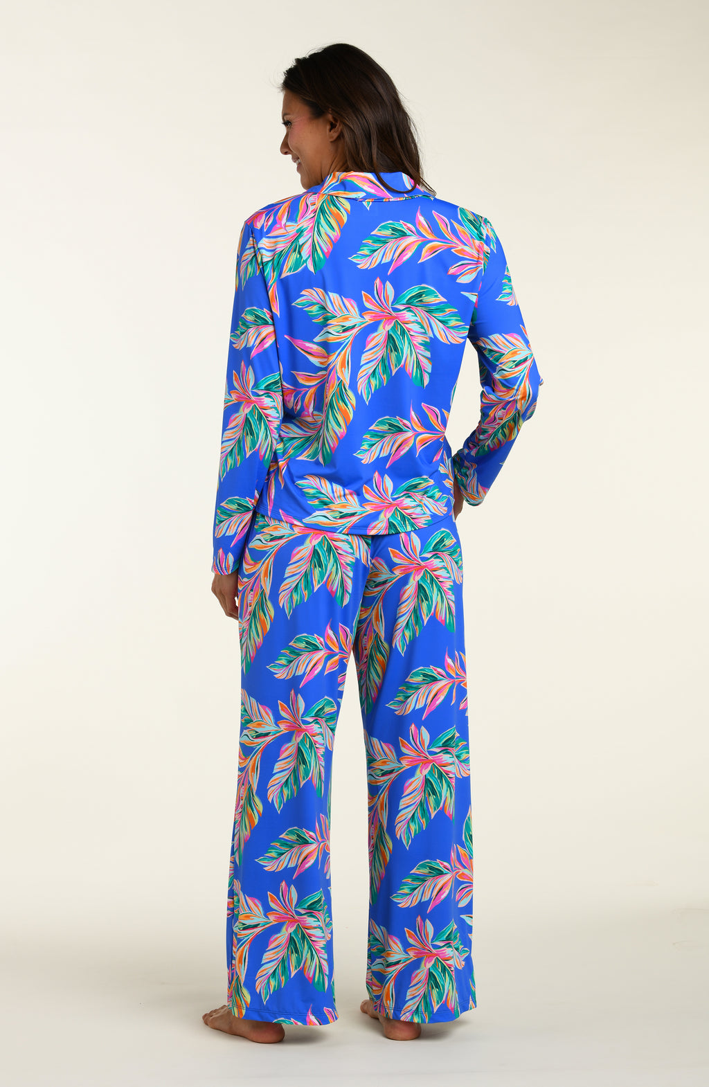Woman wearing a colorful tropical leaf pattern pajama set on a white background