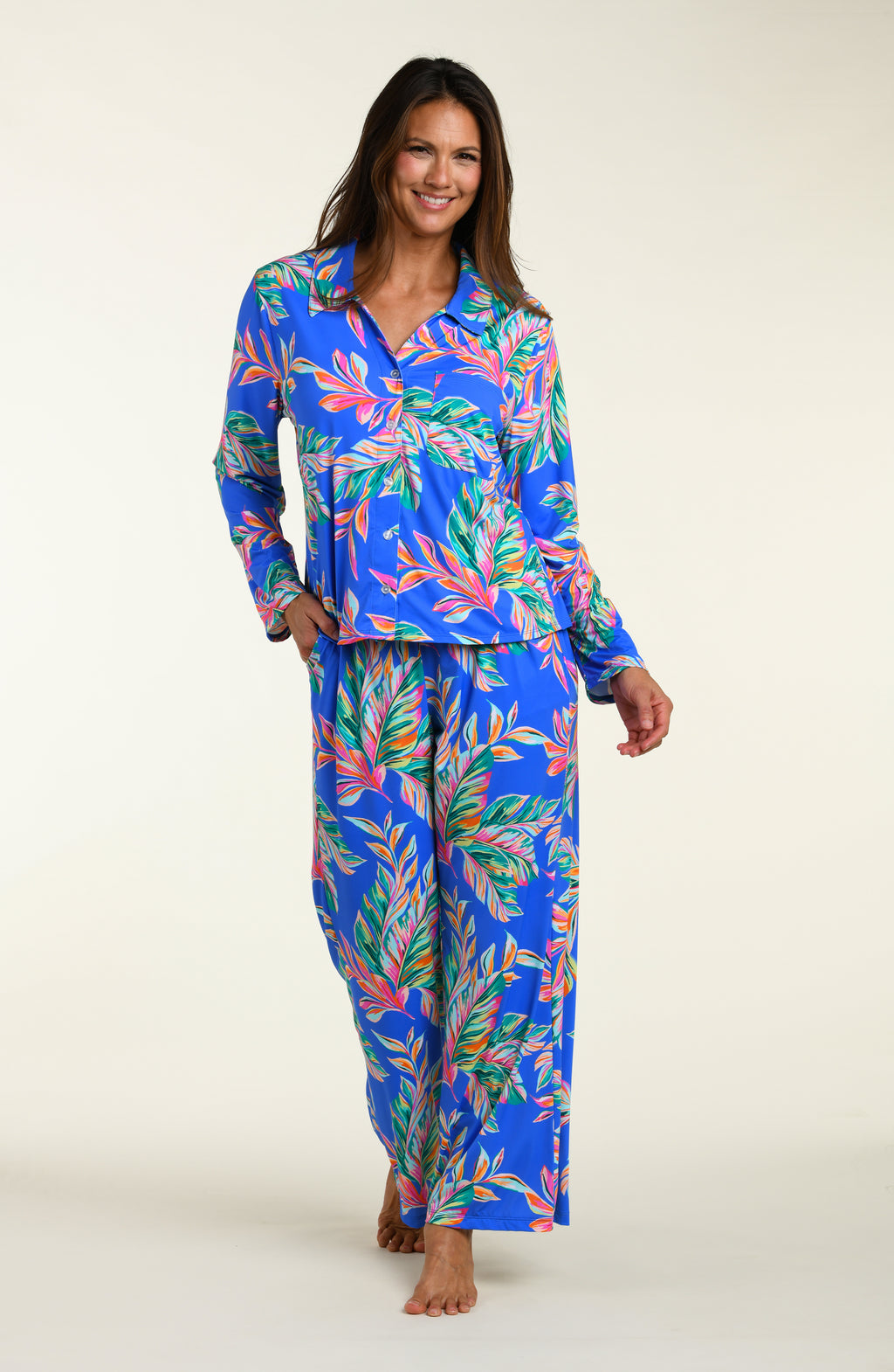 Woman wearing a colorful tropical leaf pattern pajama set on a white background