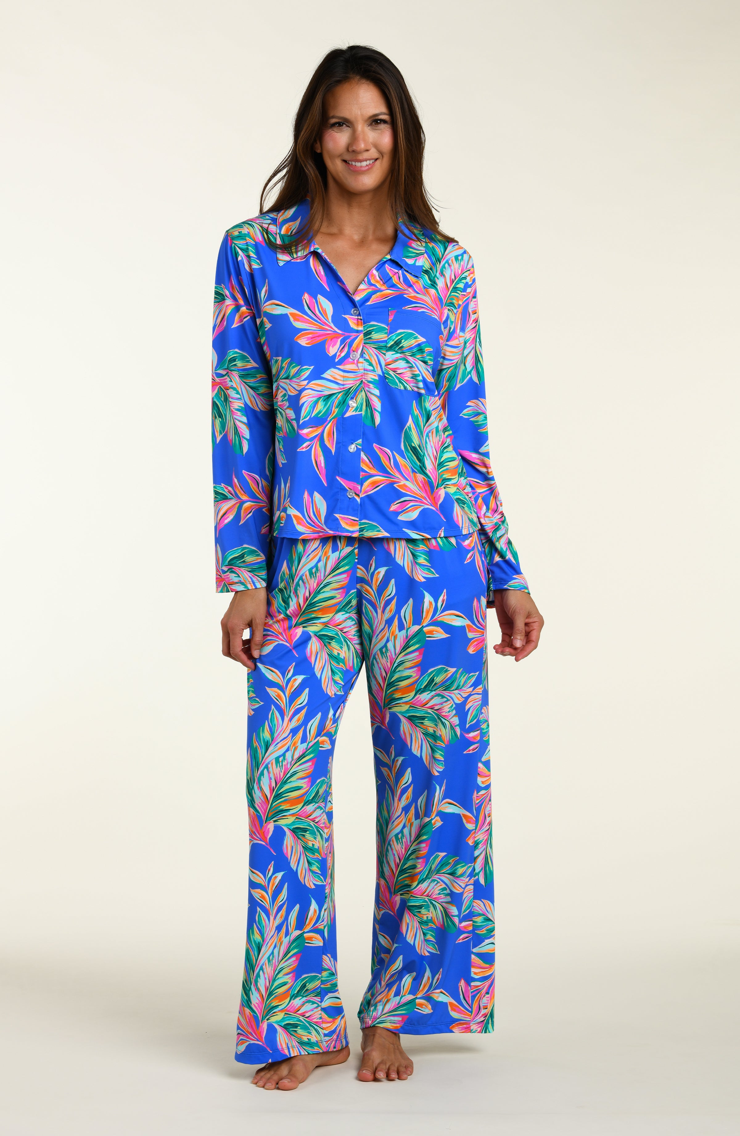 Woman wearing a colorful tropical leaf pattern pajama set on a white background
