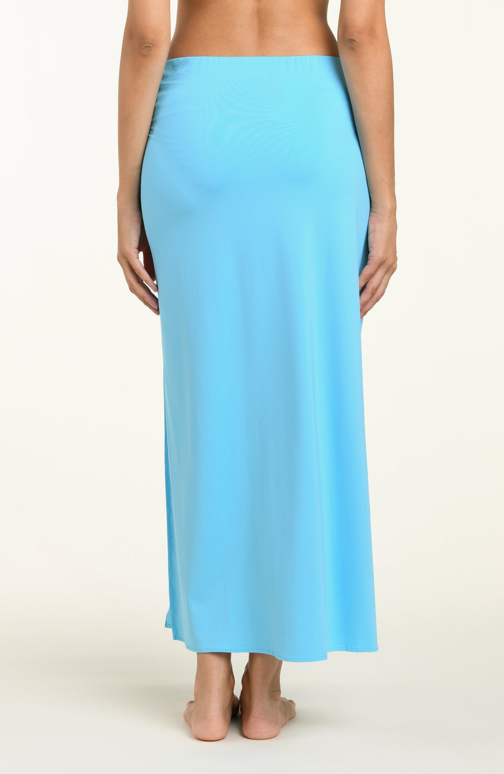 Woman wearing a light blue pareo wrap cover up against a white background.