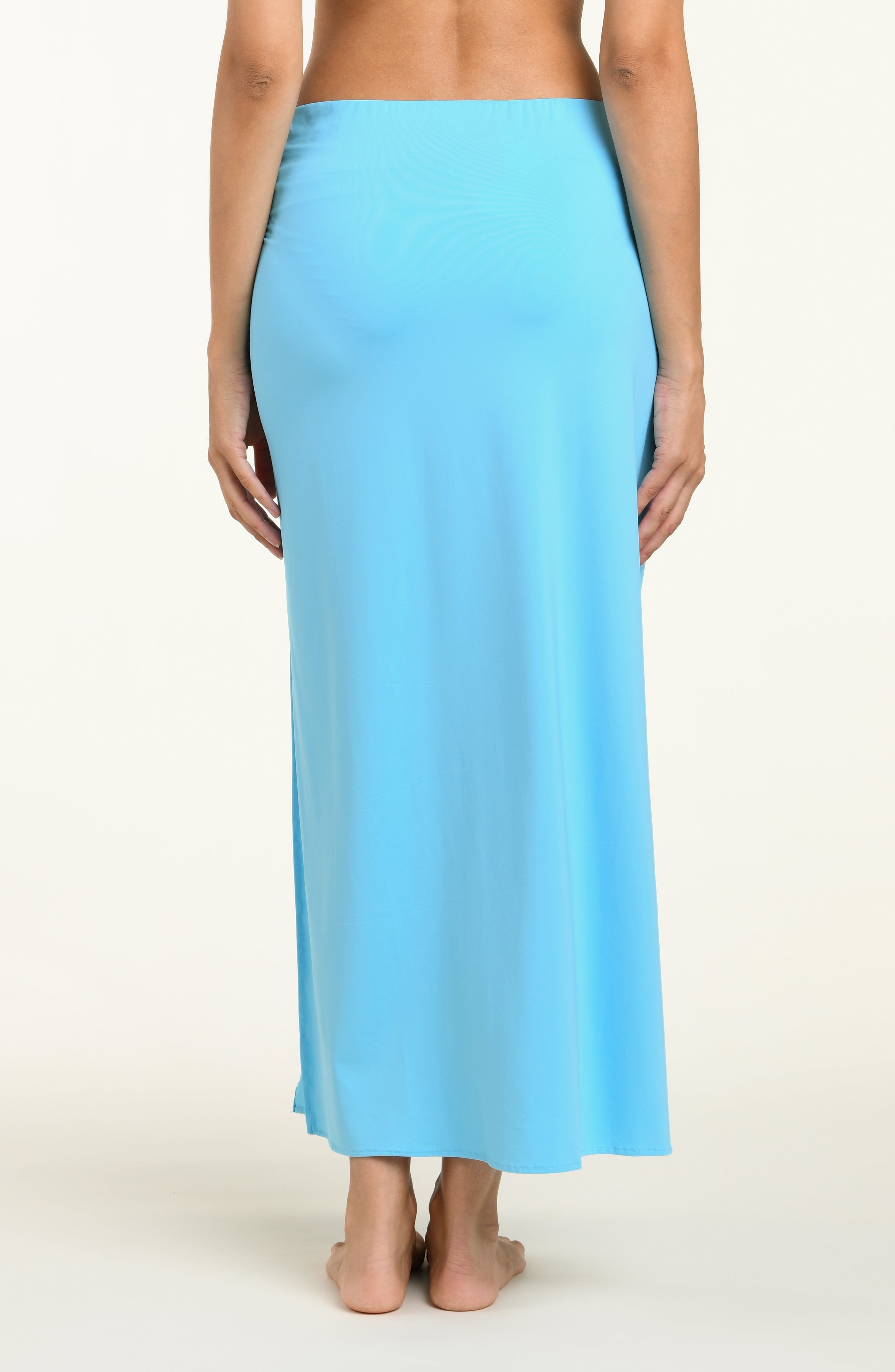 Woman wearing a light blue pareo wrap cover up against a white background.