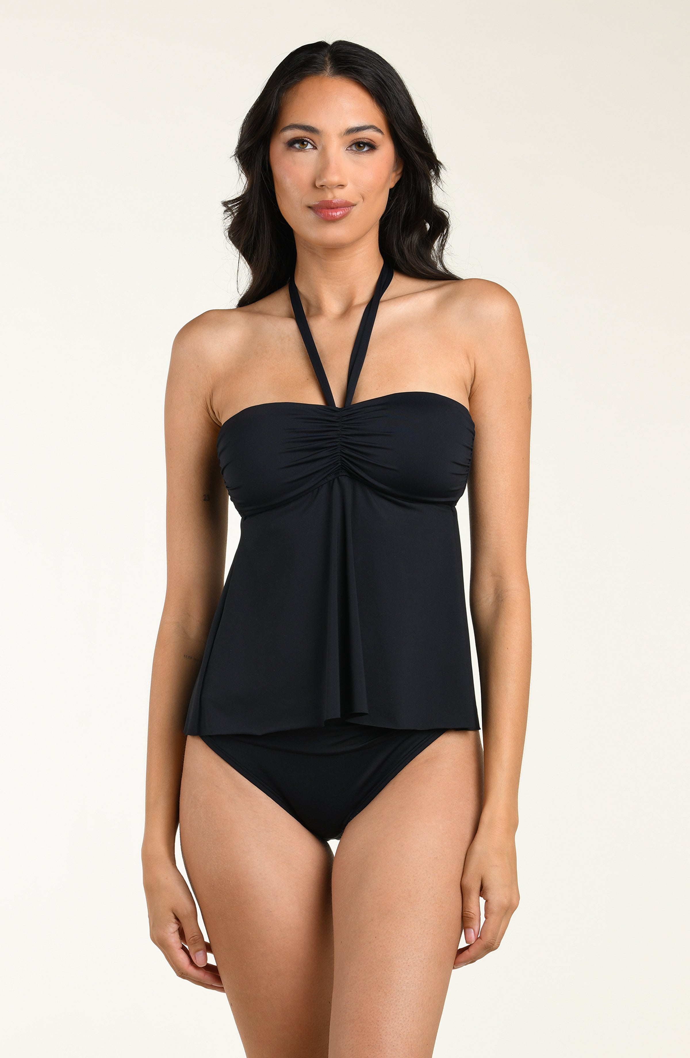 Woman wearing a black tankini top and matching bottom against a white background.