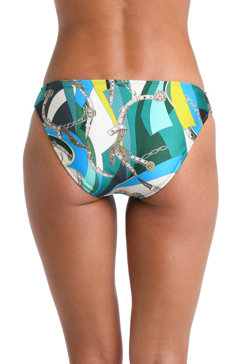 Rear view of a model wearing bikini bottoms with a colorful abstract print featuring teal, blue, yellow, white, black, and silver chain motifs on a white studio background.