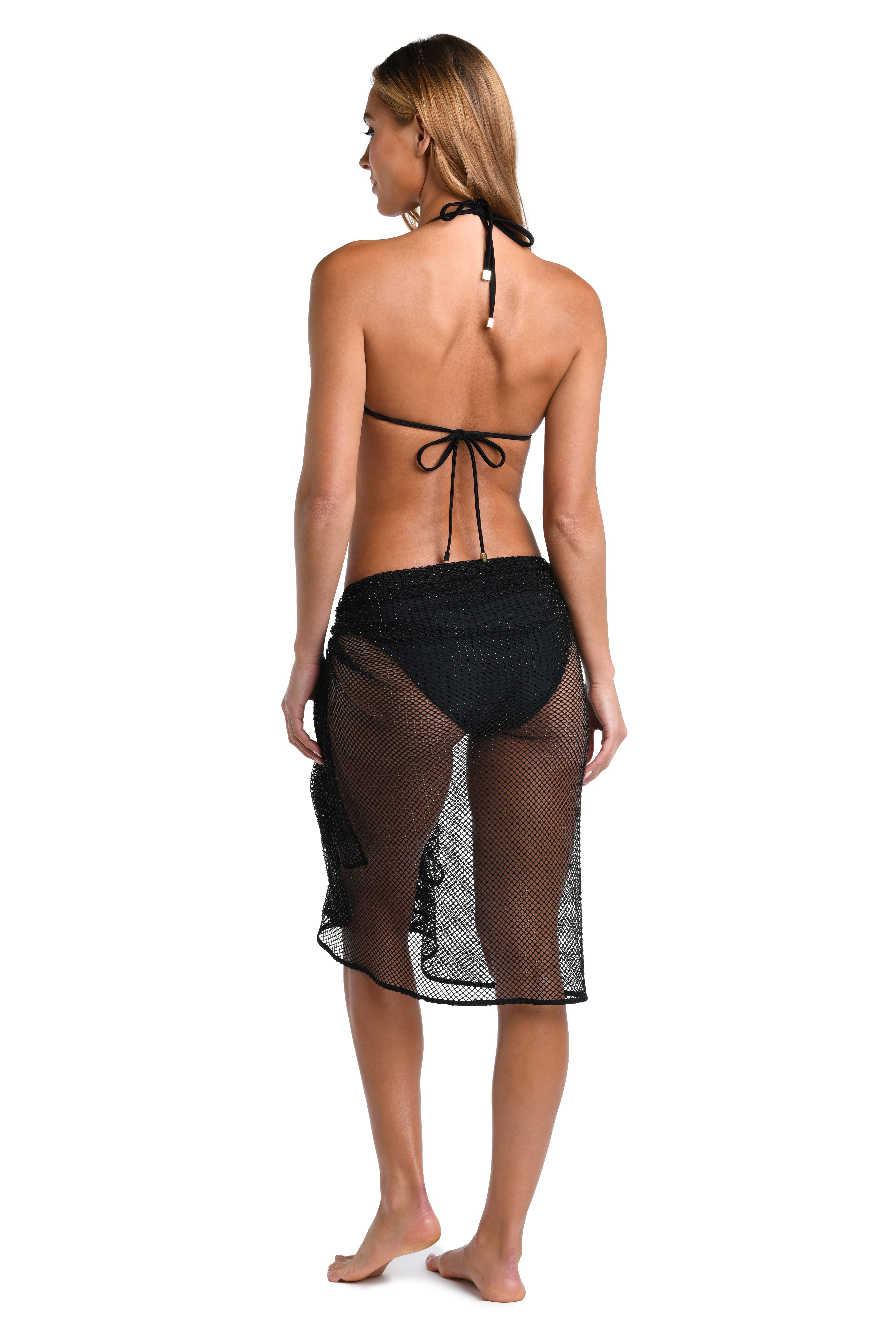 A woman wearing a black sarong over a black bikini top and bottom against a white background. 