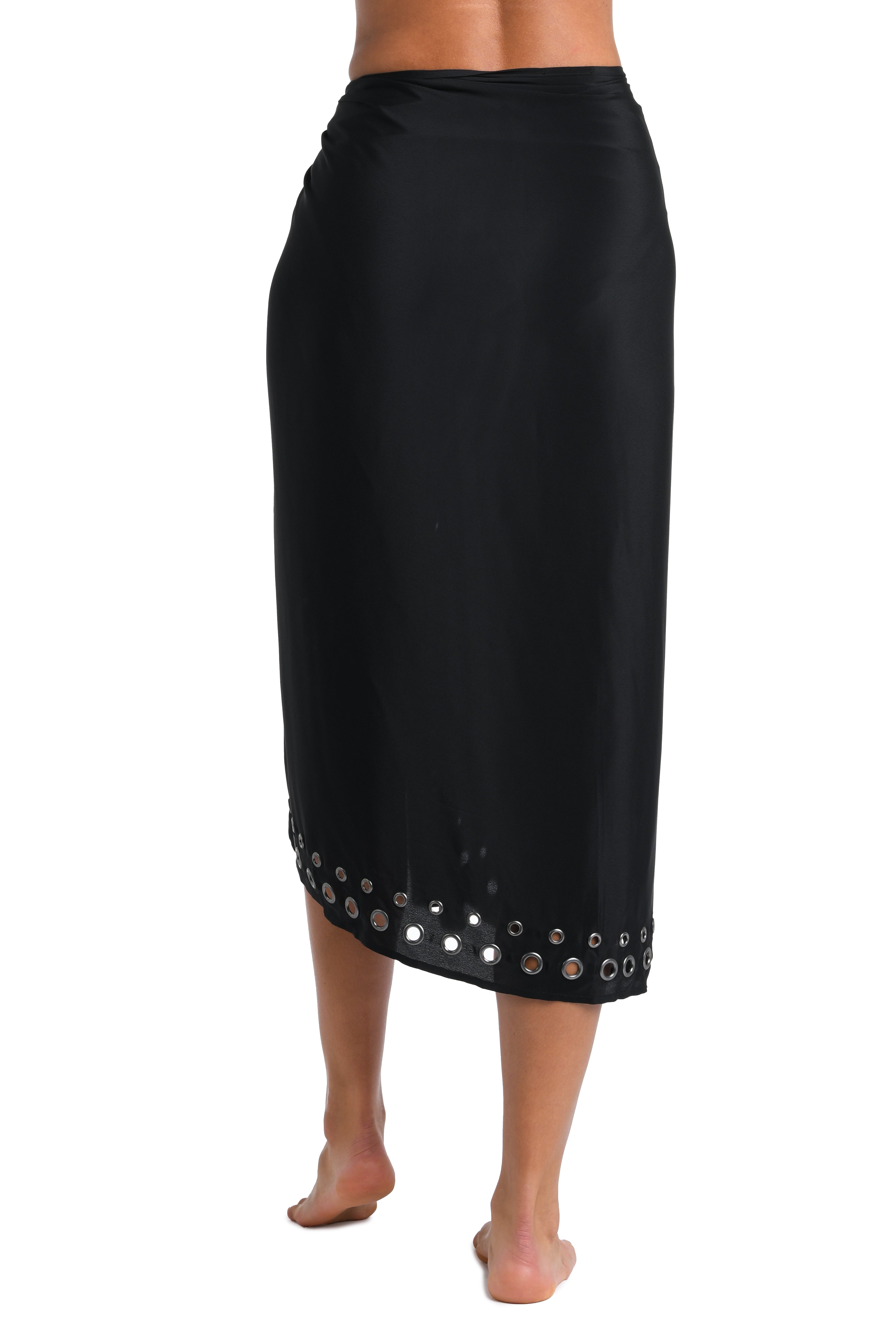 A black wrap skirt with a row of silver-toned circular studs along the hem, shown on a model from the back against a plain white background.