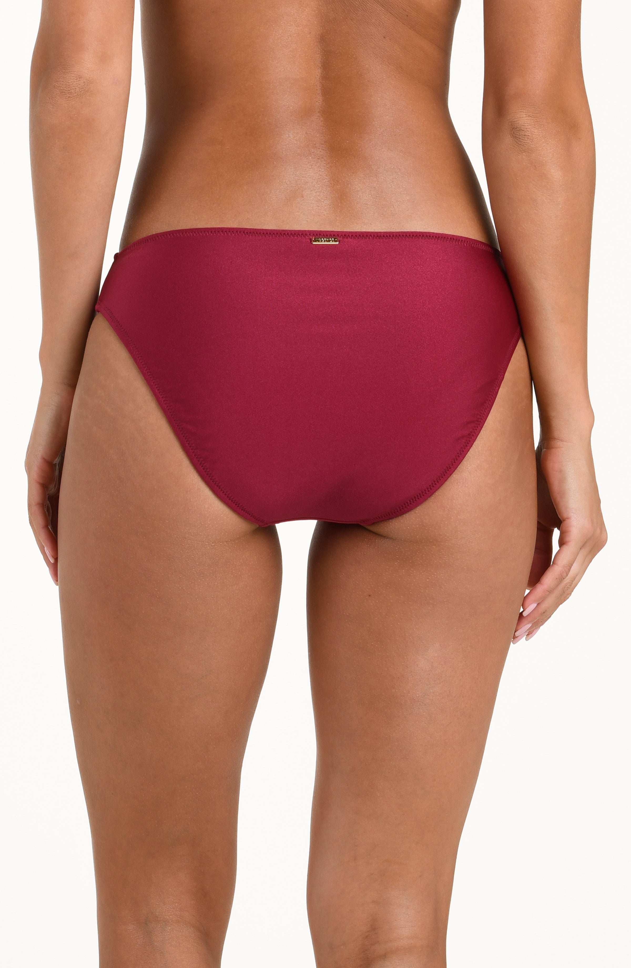 Woman wearing a black cherry bikini bottom against a white background. 