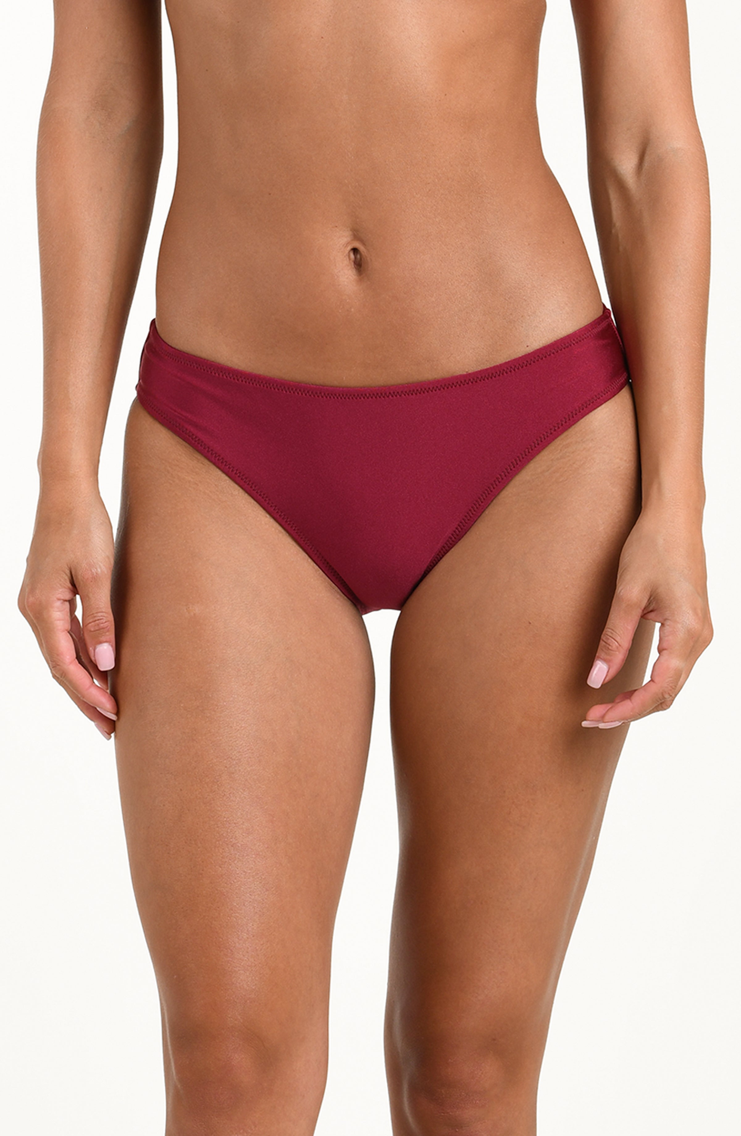 Woman wearing a black cherry bikini bottom against a white background. 