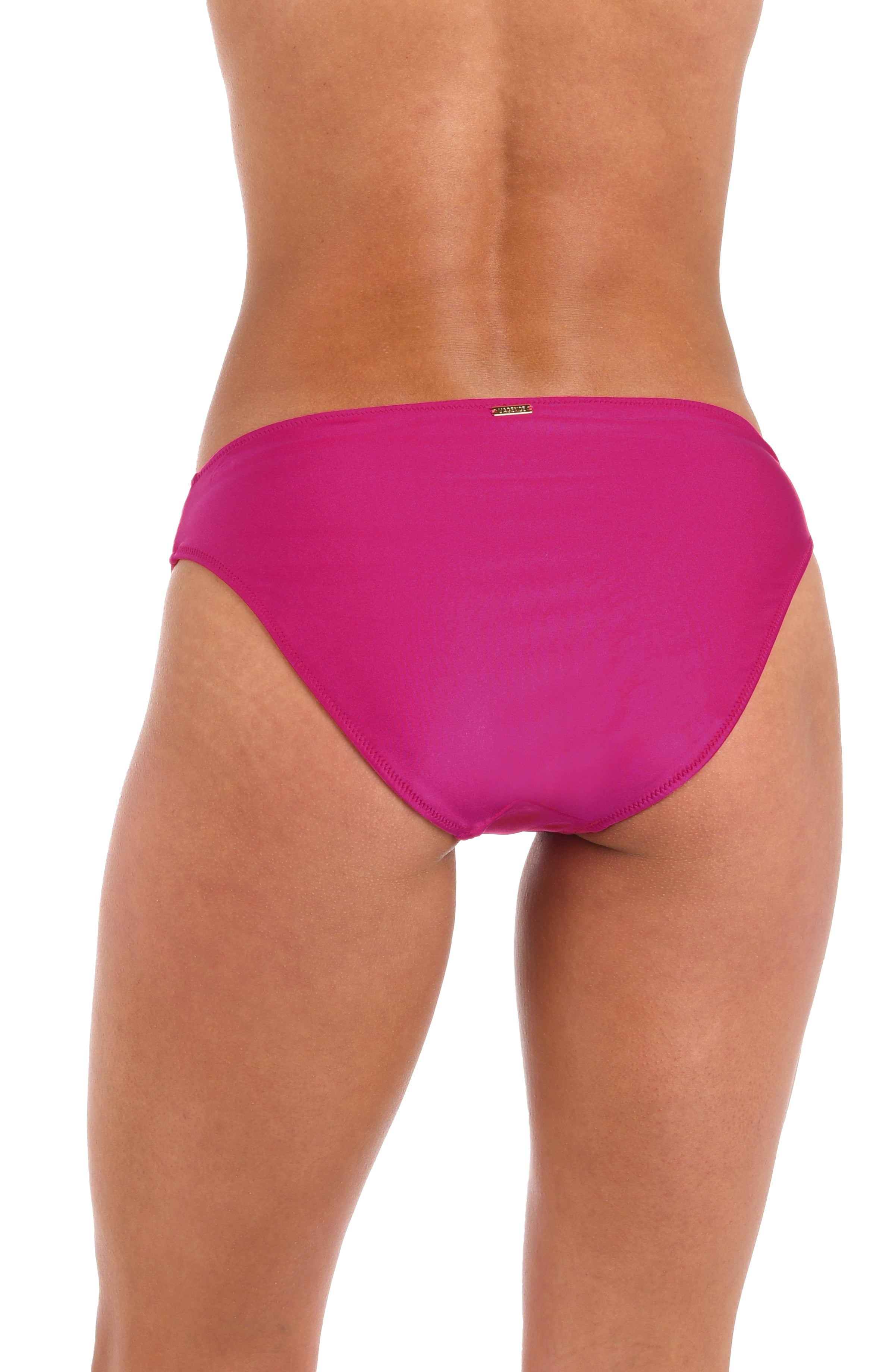 Woman wearing a fuchsia colored hipster bikini bottom against a white background. 