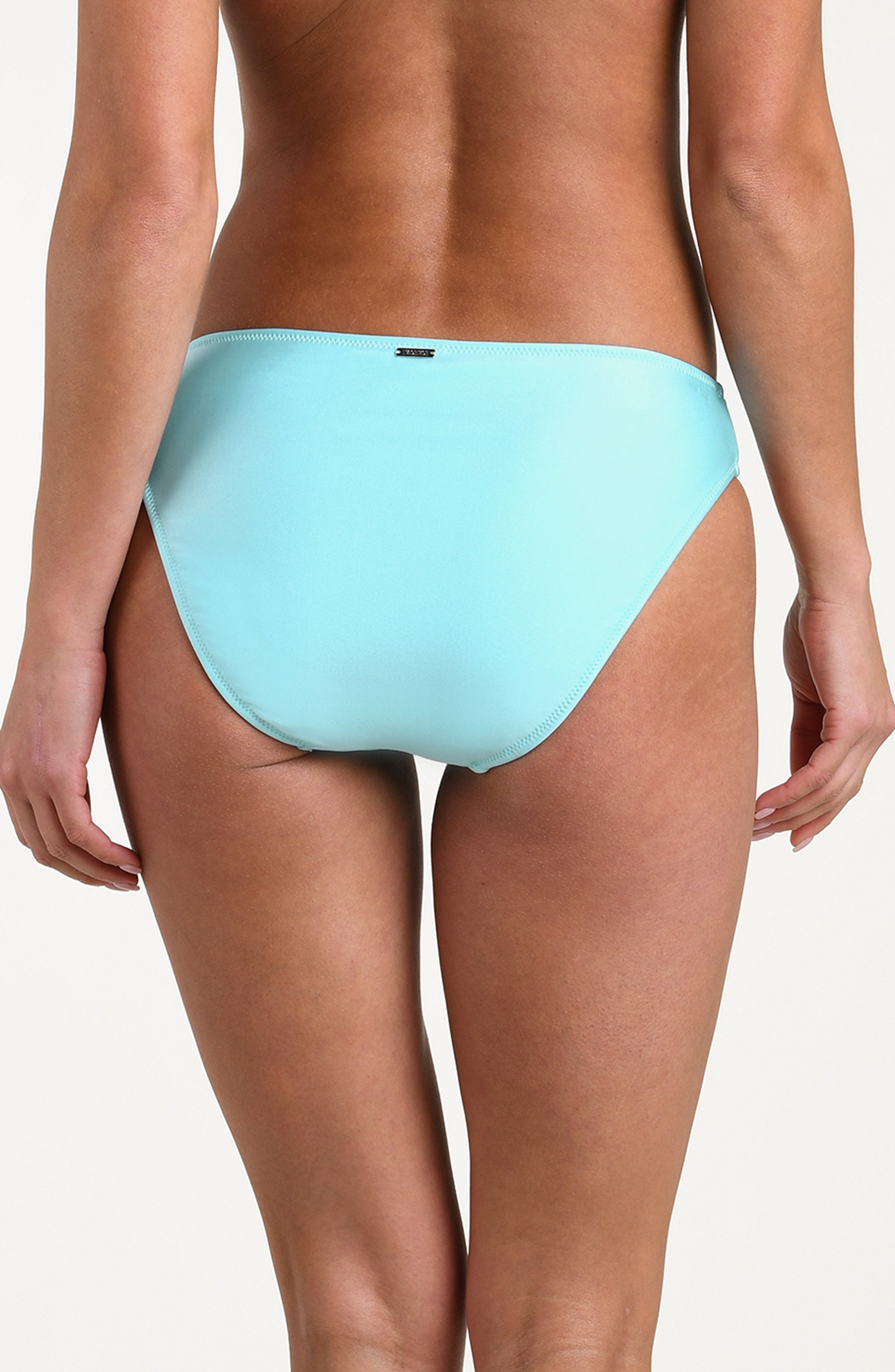 Woman wearing an aqua blue colored bikini bottom against a white background. 