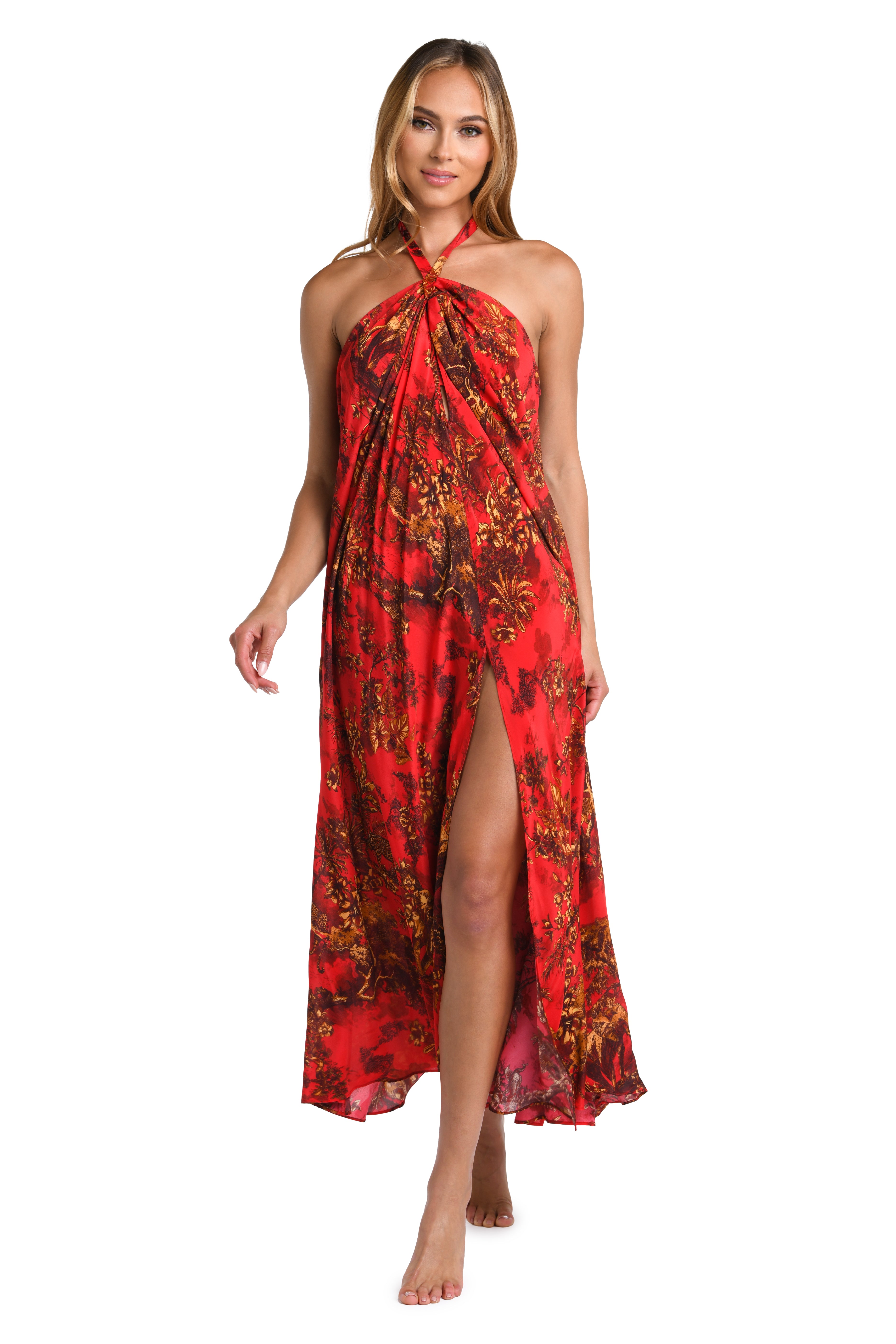 A woman modeling a red halter-neck maxi dress with a brown and black abstract floral print, featuring a high side slit, set against a plain white background.