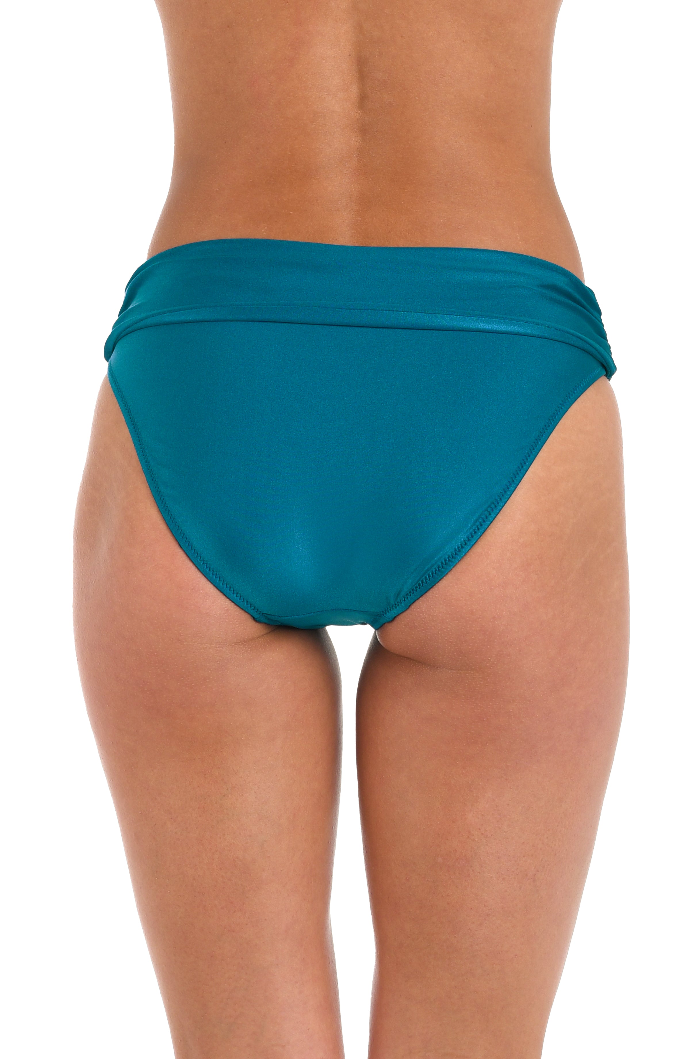 Woman wearing a teal colored bikini bottom against a white background.