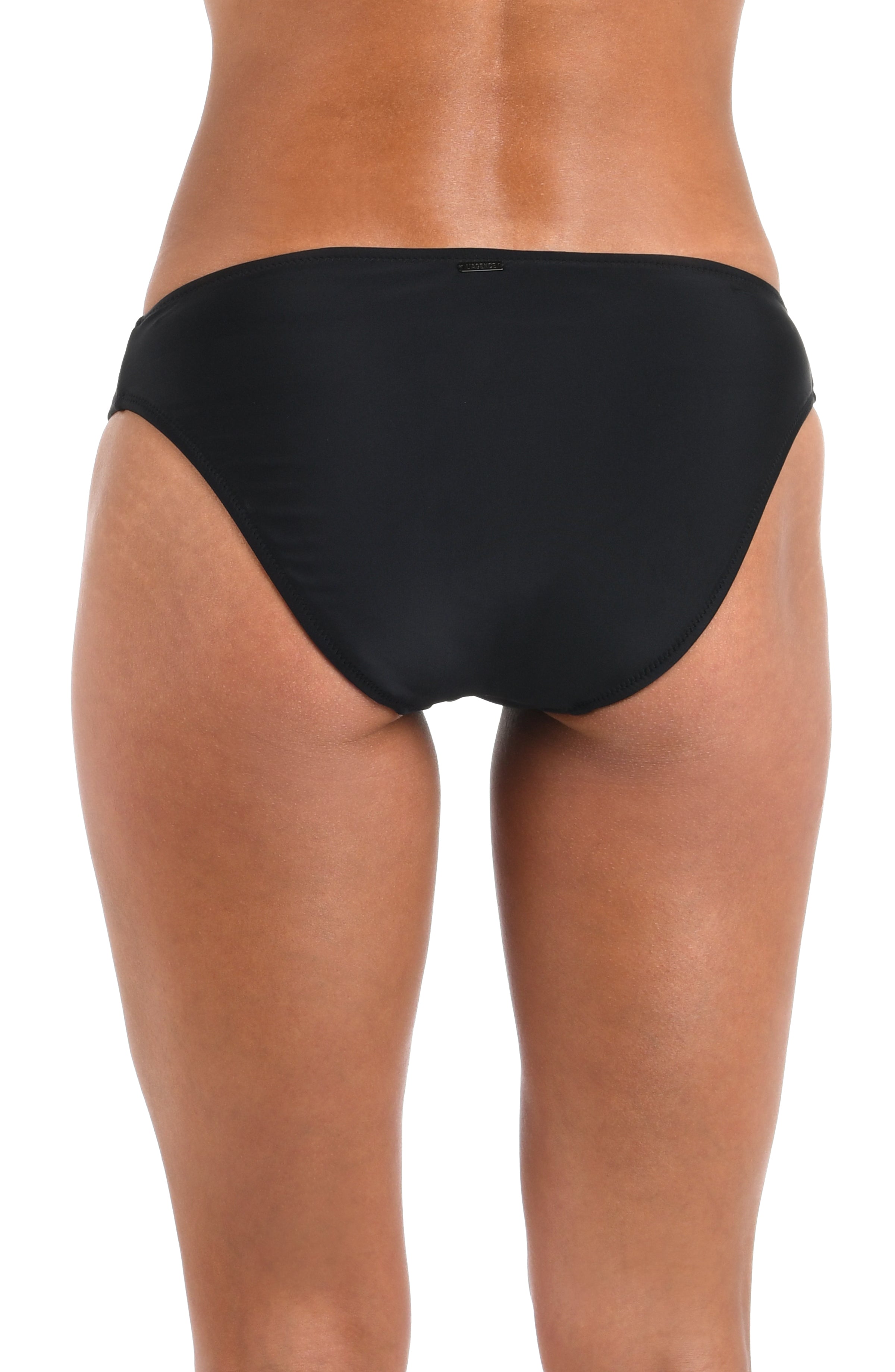 Rear view of a model wearing black bikini bottoms against a plain white background.