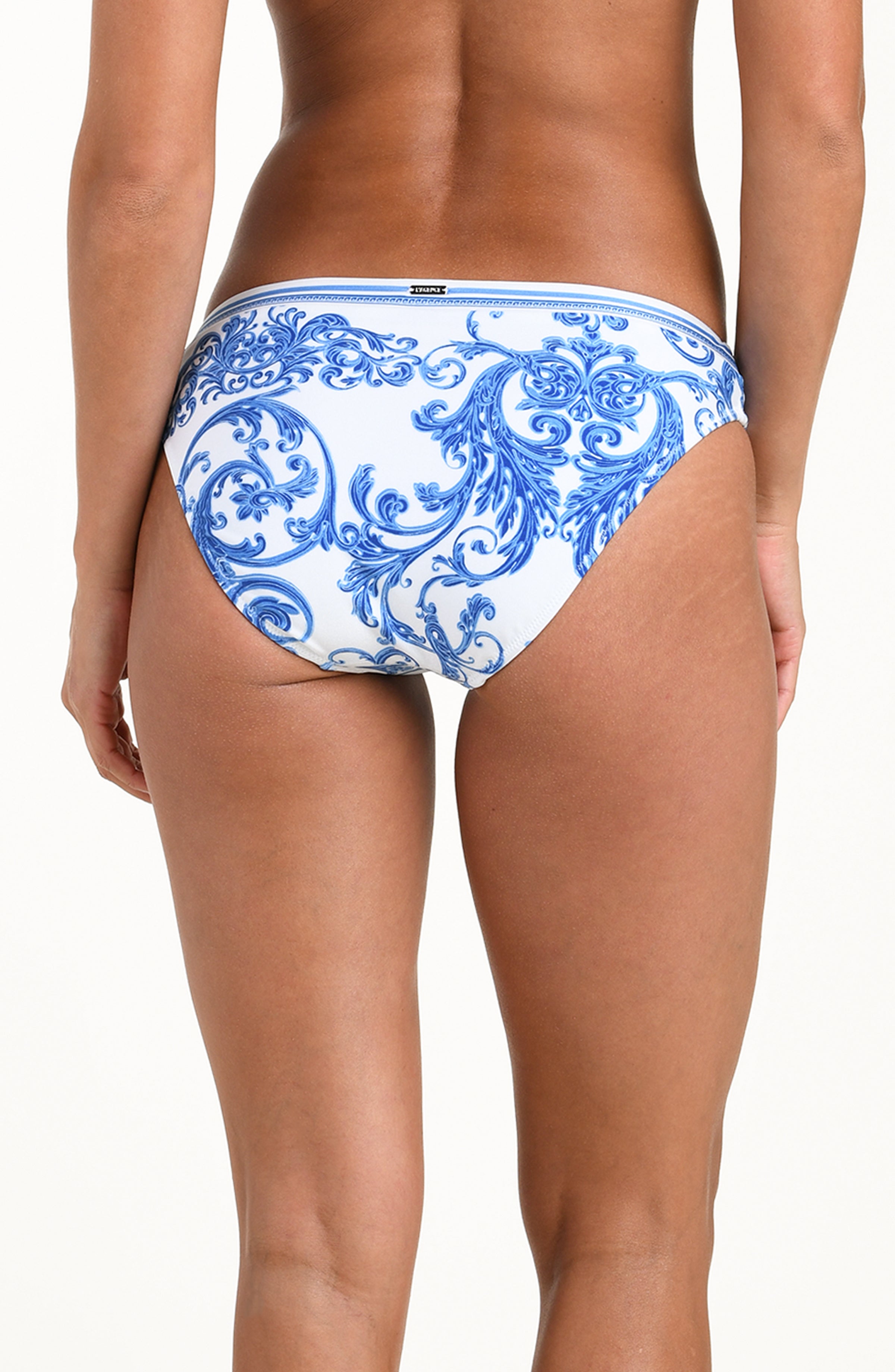 Woman wearing a white and blue bikini bottom against a white background.