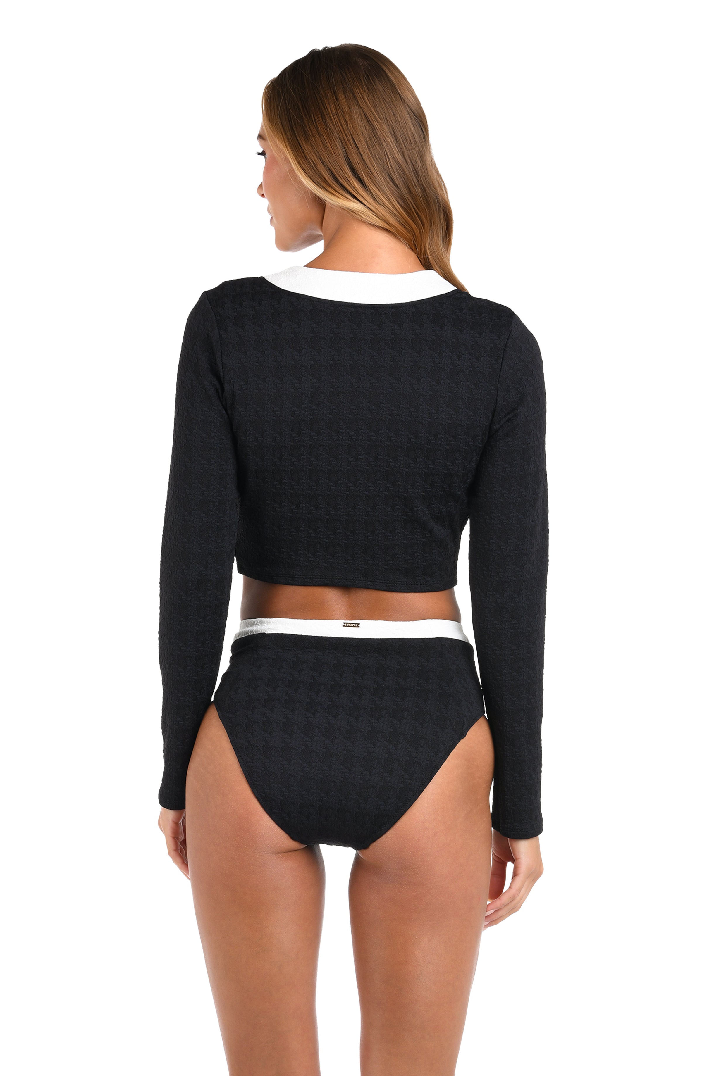 Woman wearing a black long-sleeve top and high-waisted black bikini bottom on a white background