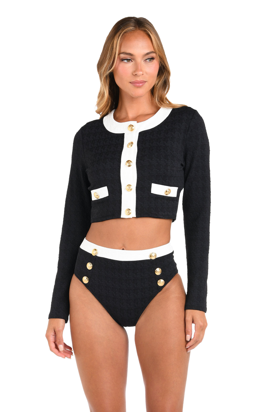 Woman wearing a black cardigan with white accents and high-waisted black shorts on a white background