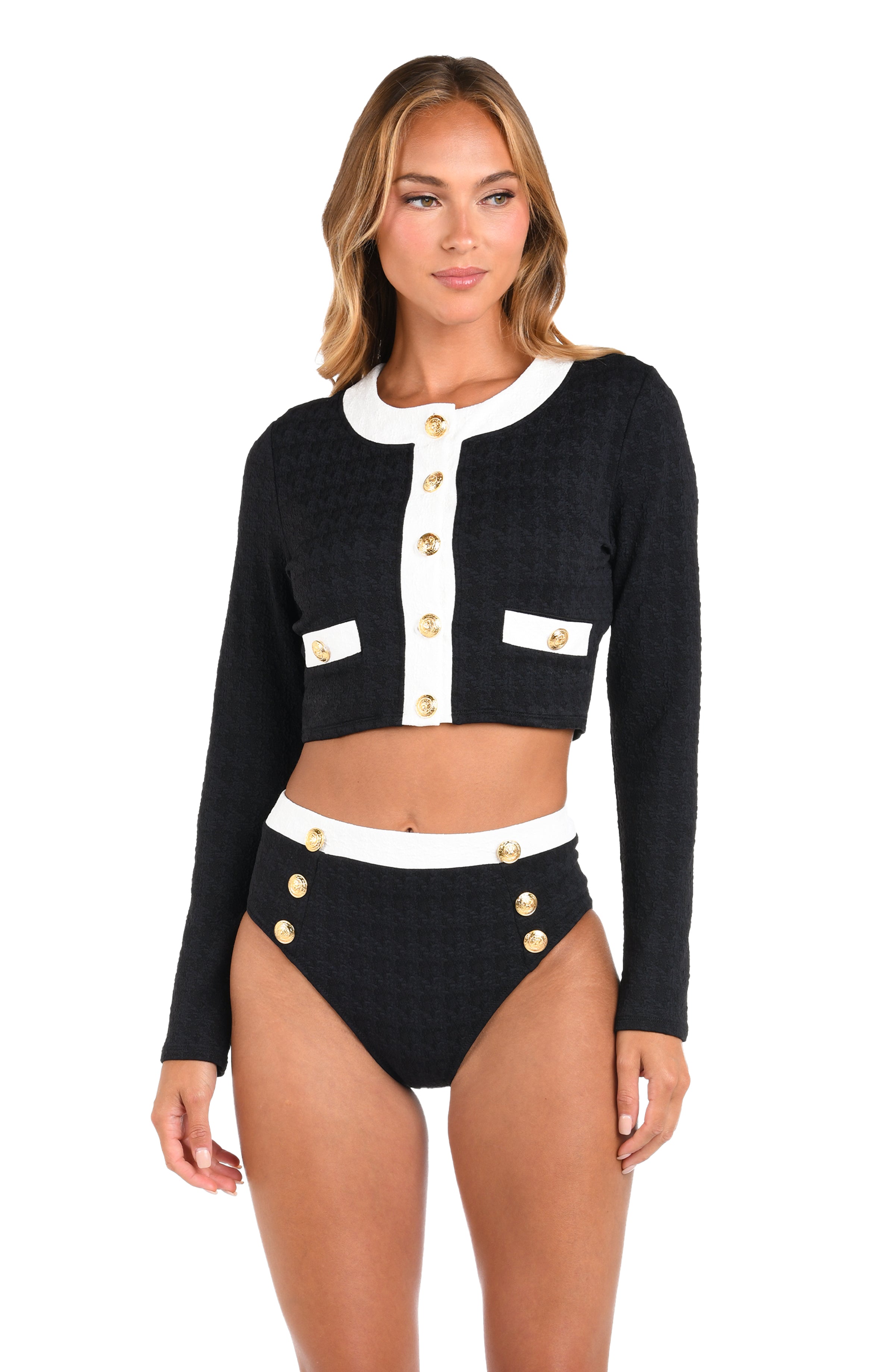 Woman wearing a black cardigan with white accents and high-waisted black shorts on a white background