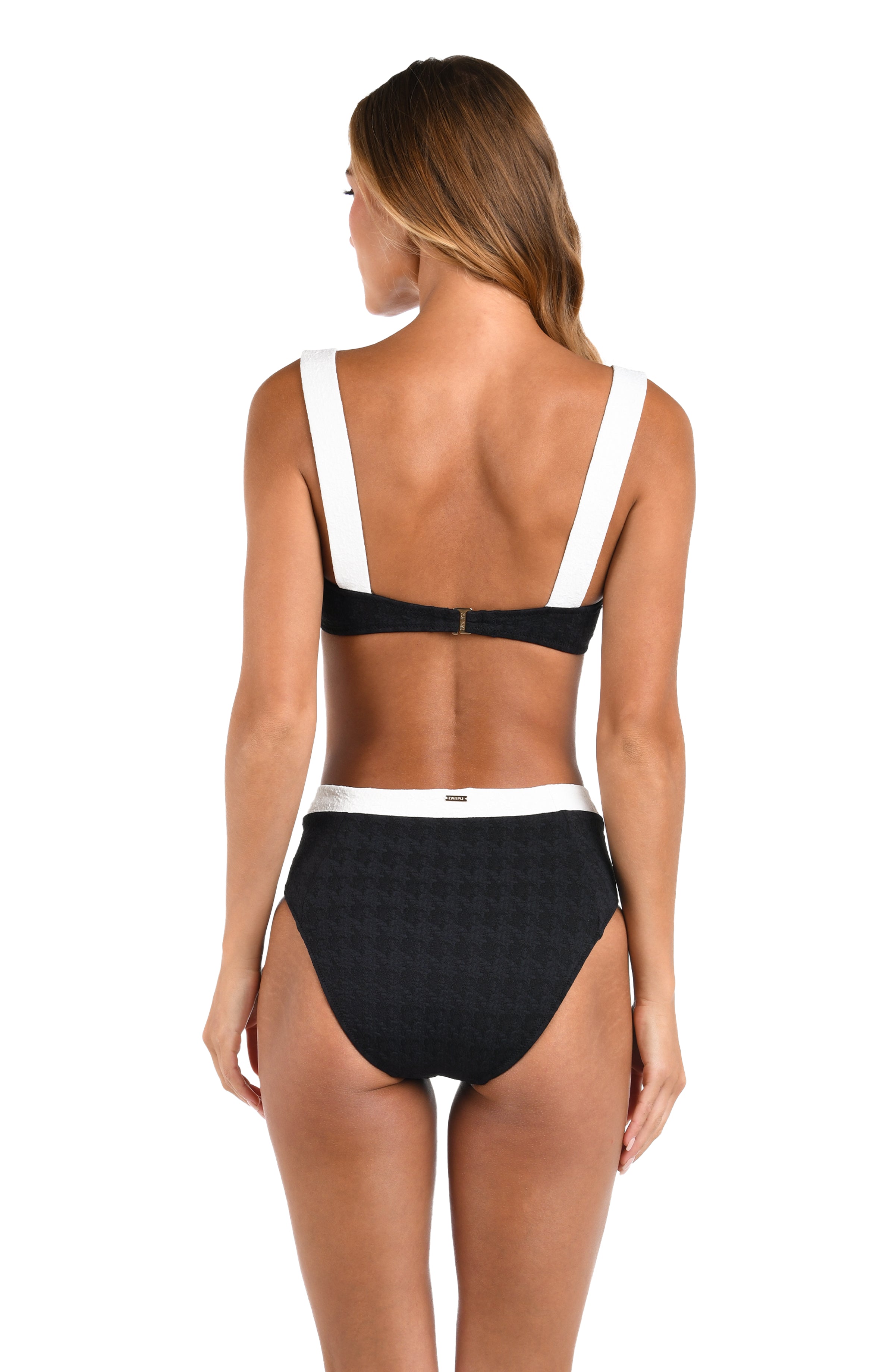 Woman wearing a black bikini with white straps on a white background