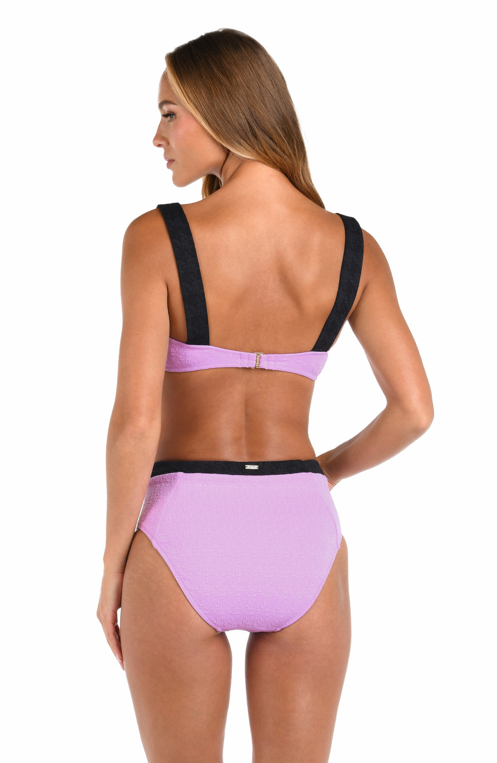 A woman shown from the back wearing a lavender and black two-piece bikini set against a plain white background.