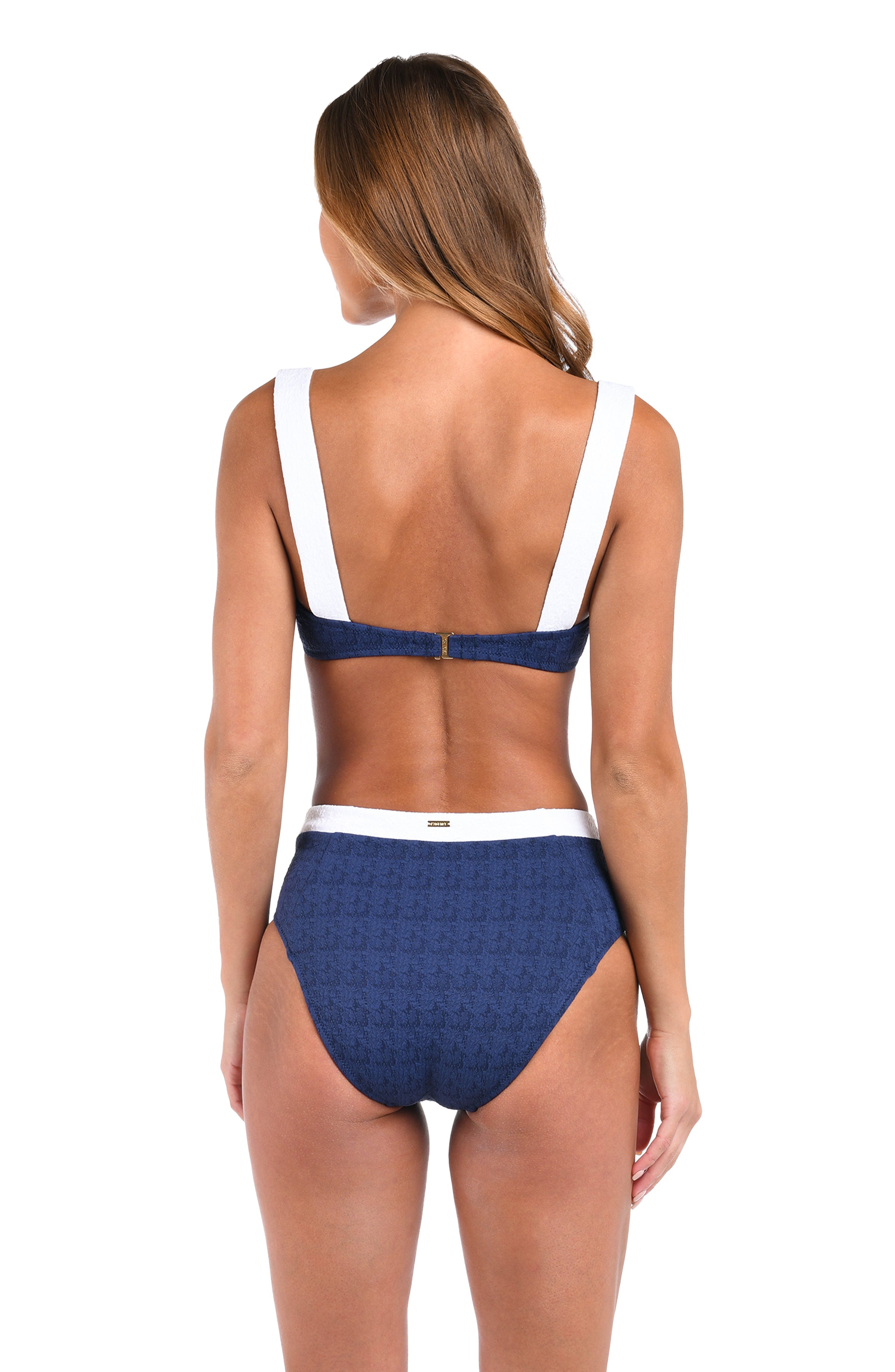 A woman shown from the back wearing a two-piece bikini. The swimsuit features a navy blue patterned fabric with white straps and a white waistband.