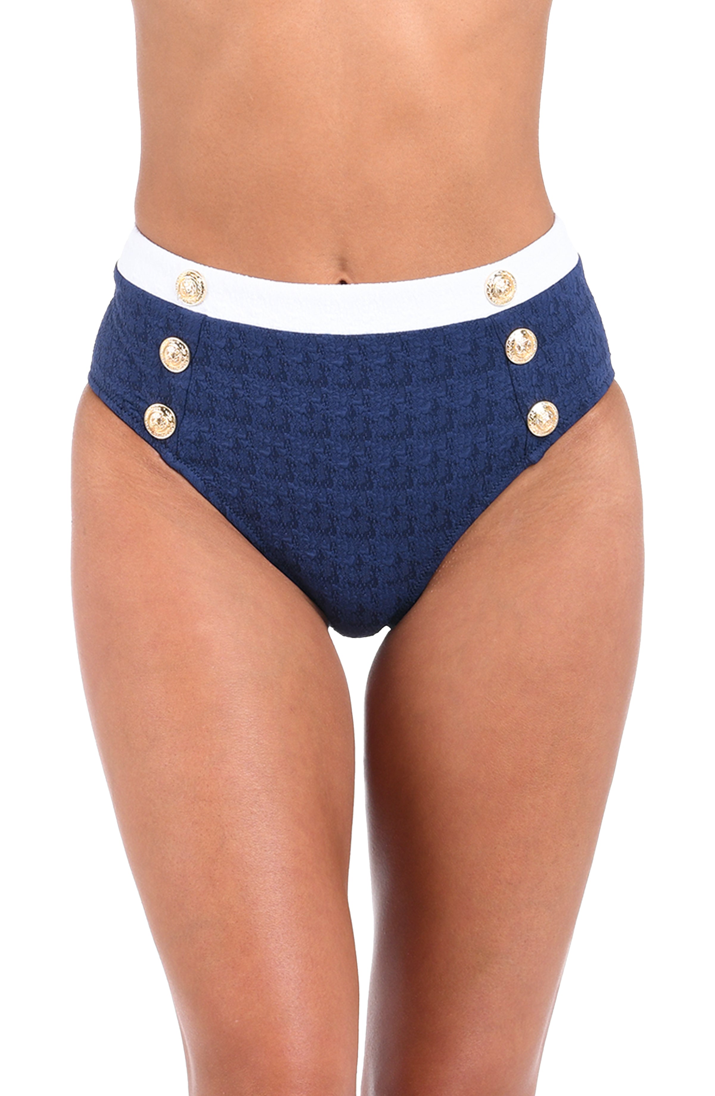 A close-up of a model wearing high-waisted navy blue bikini bottoms with a white waistband and decorative gold buttons on the sides, set against a plain white background.