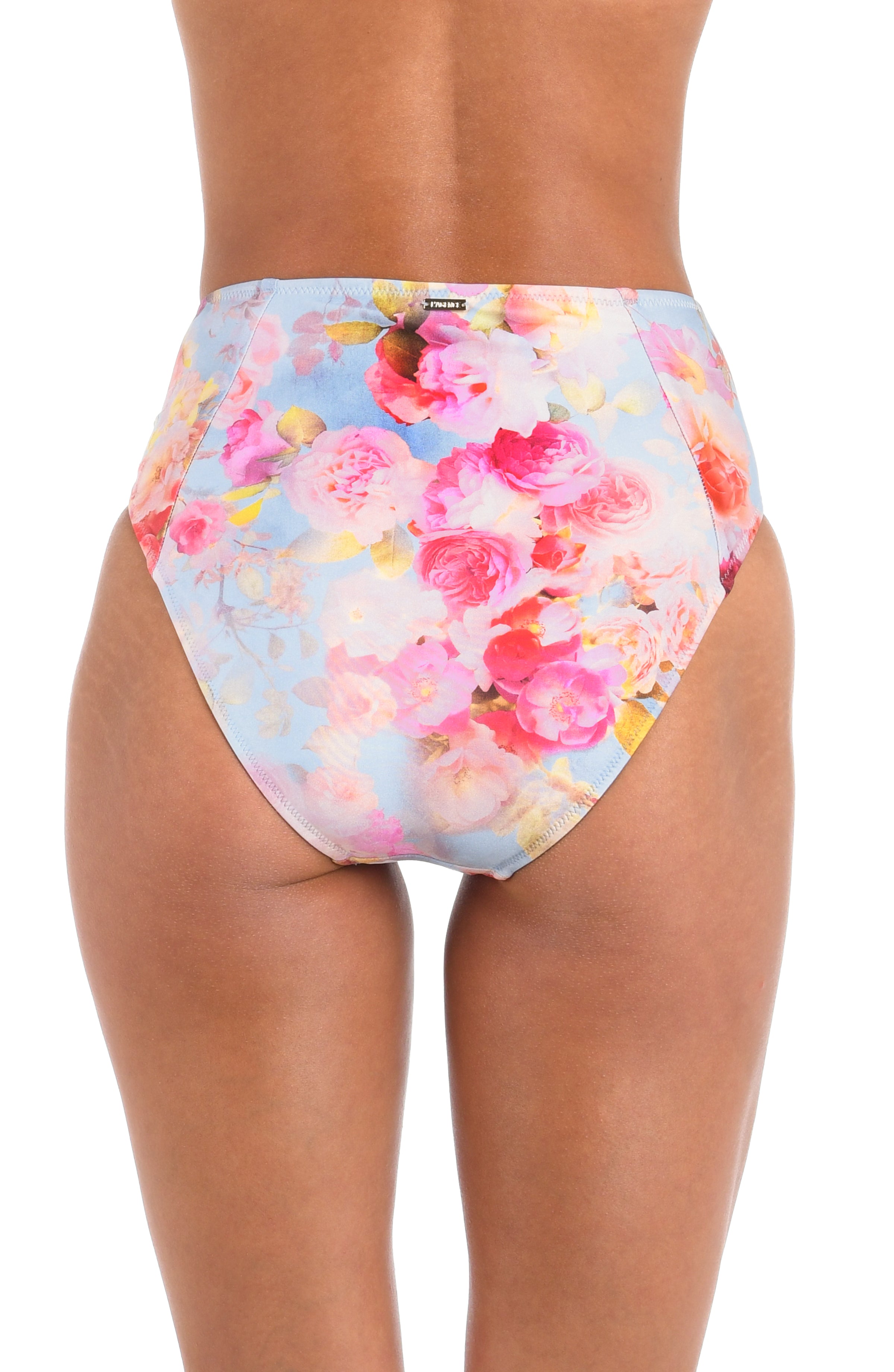 Woman wearing a light multicolored floral printed high waisted bikini bottom against a white background. 