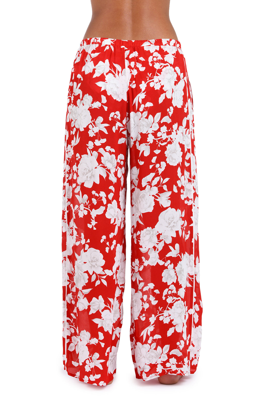 Woman wearing red multicolored floral printed cover up pants against a white background. 