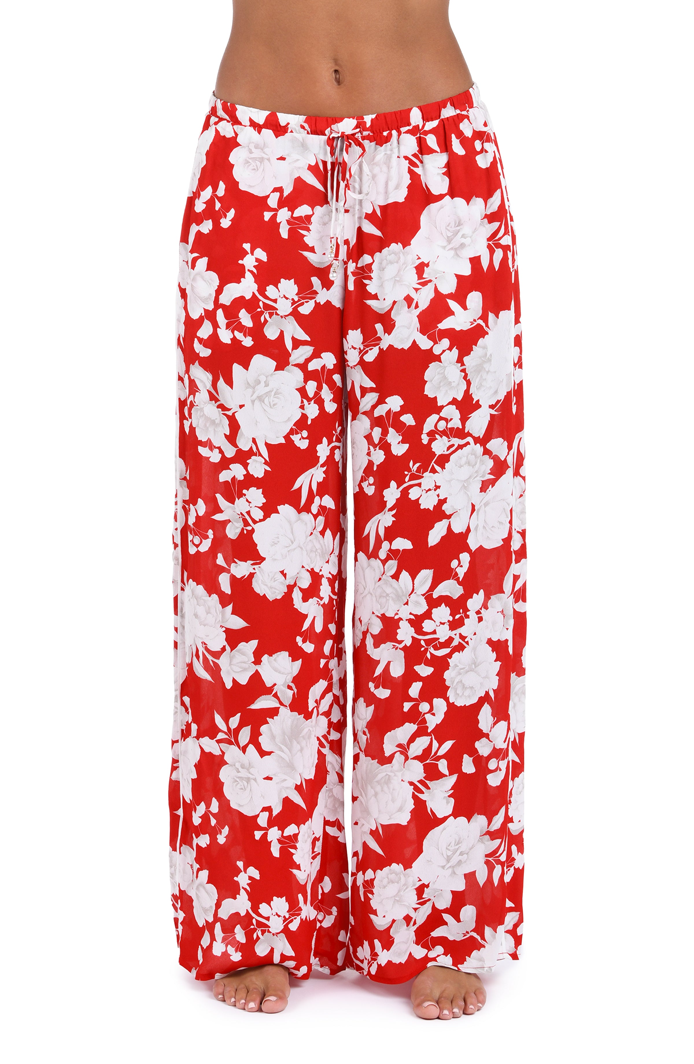 Woman wearing red multicolored floral printed cover up pants against a white background. 
