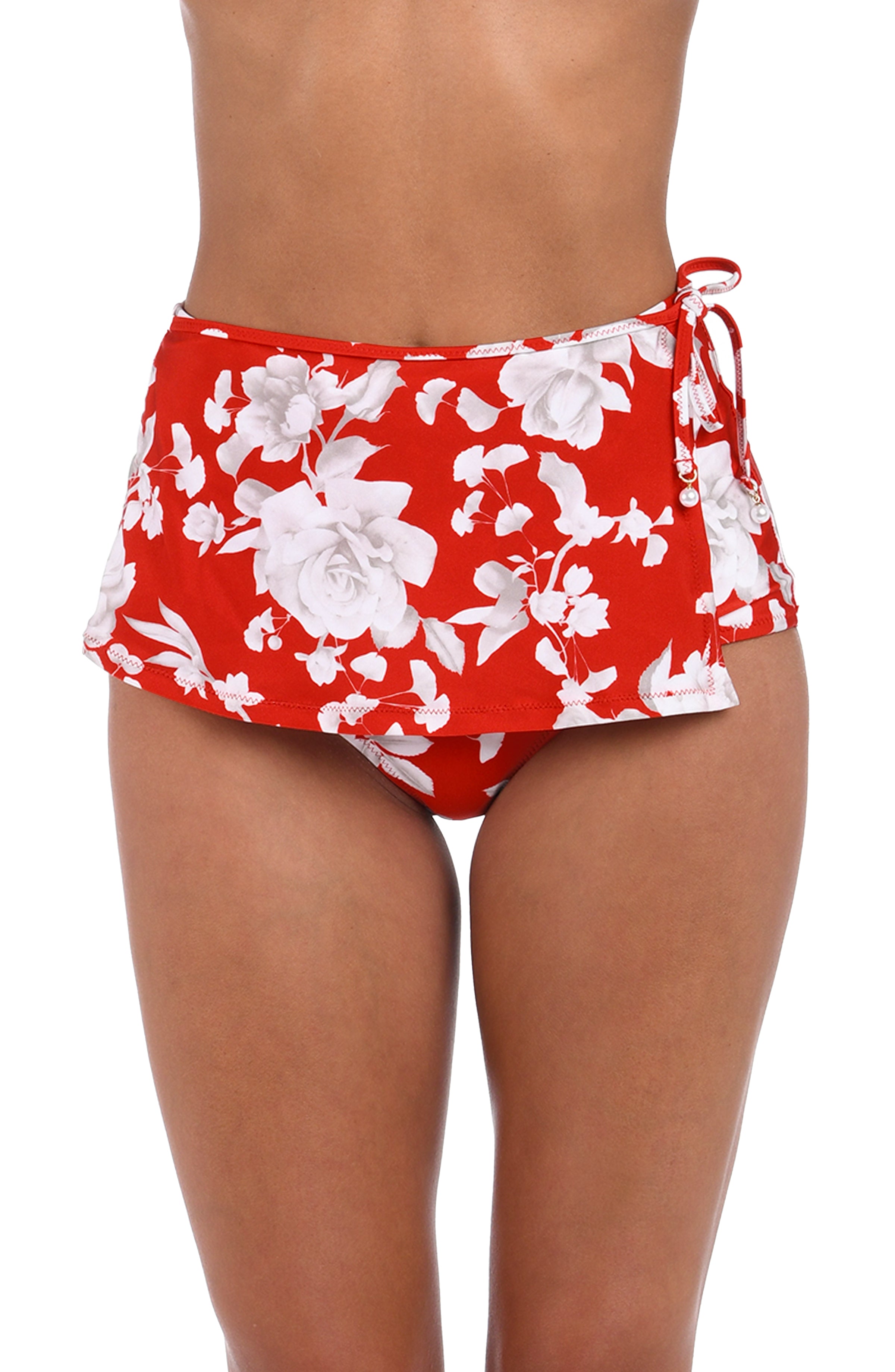 Red and white floral print swim skirt shown on a model, featuring a side tie detail on the right hip.