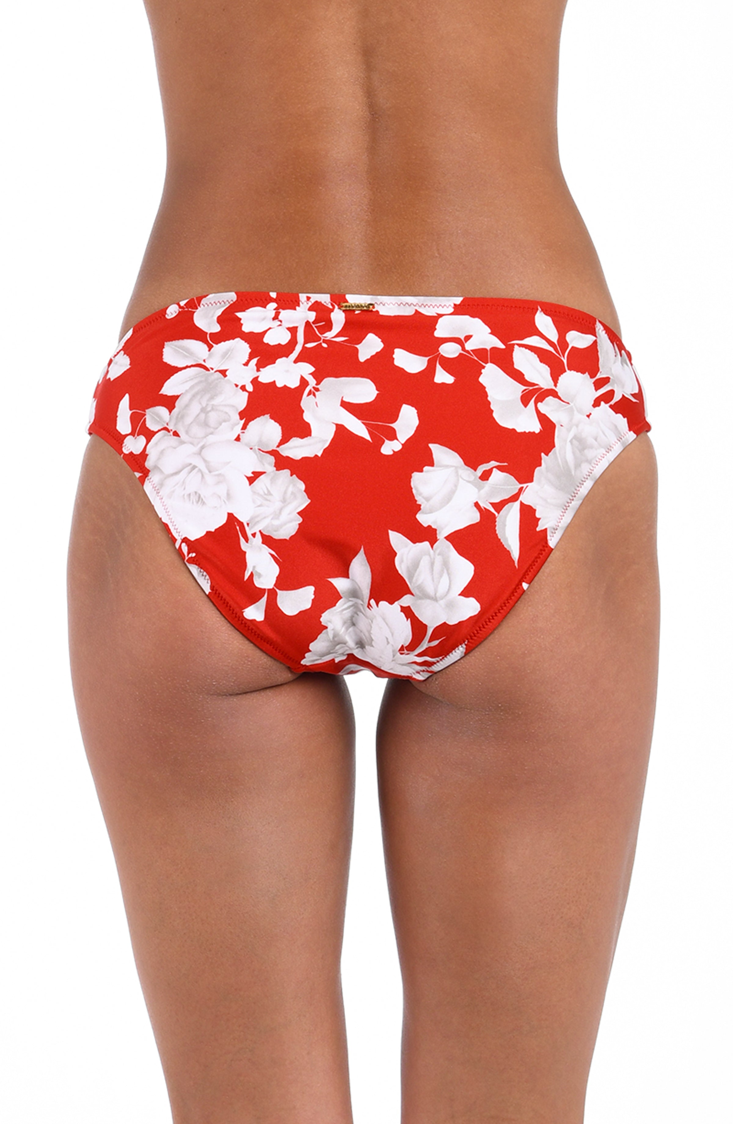 Woman wearing a red and white multicolored tropical printed hipster bikini bottom against a white background. 