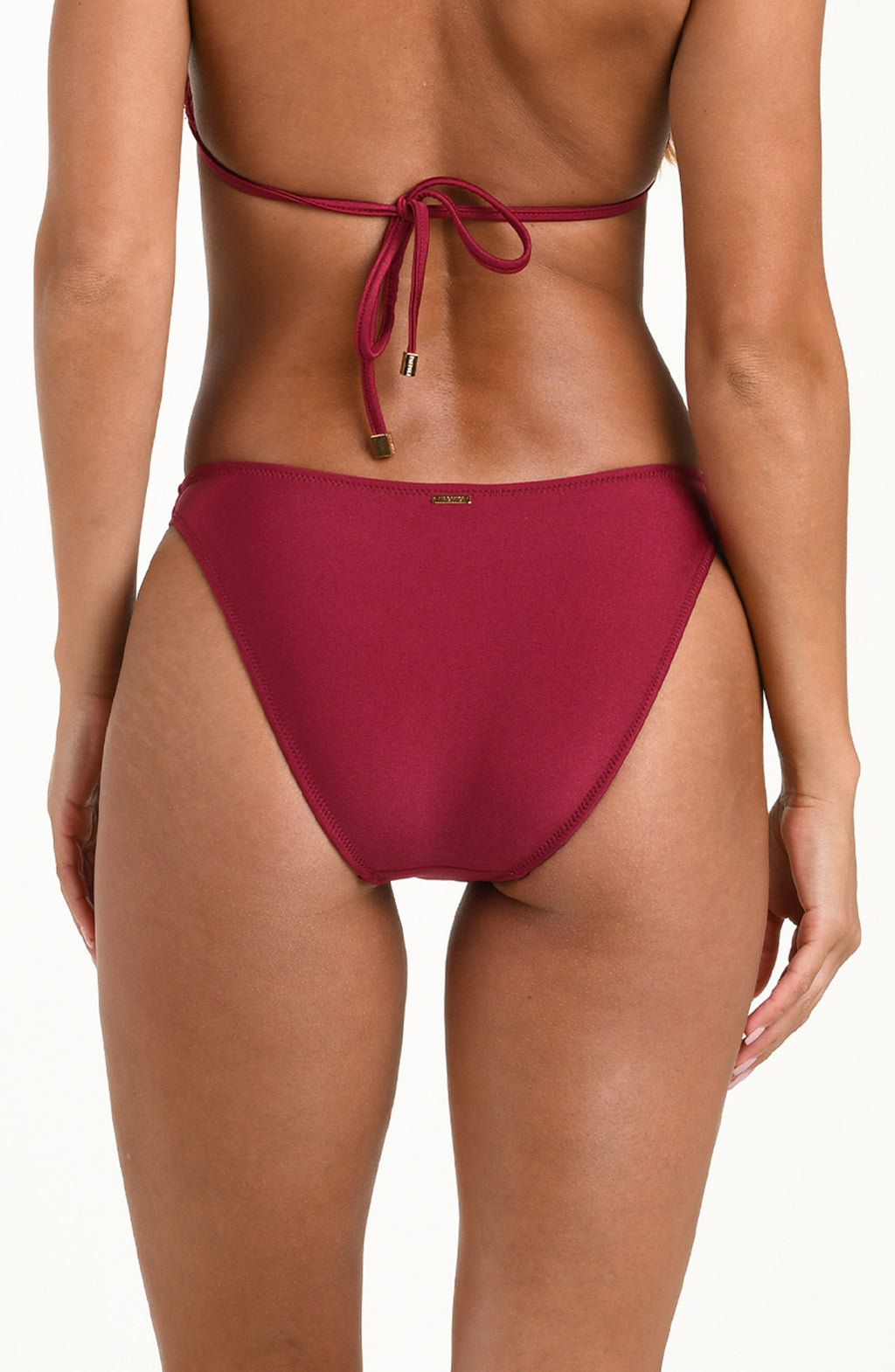 Woman wearing a black cherry bikini bottom against a white background.