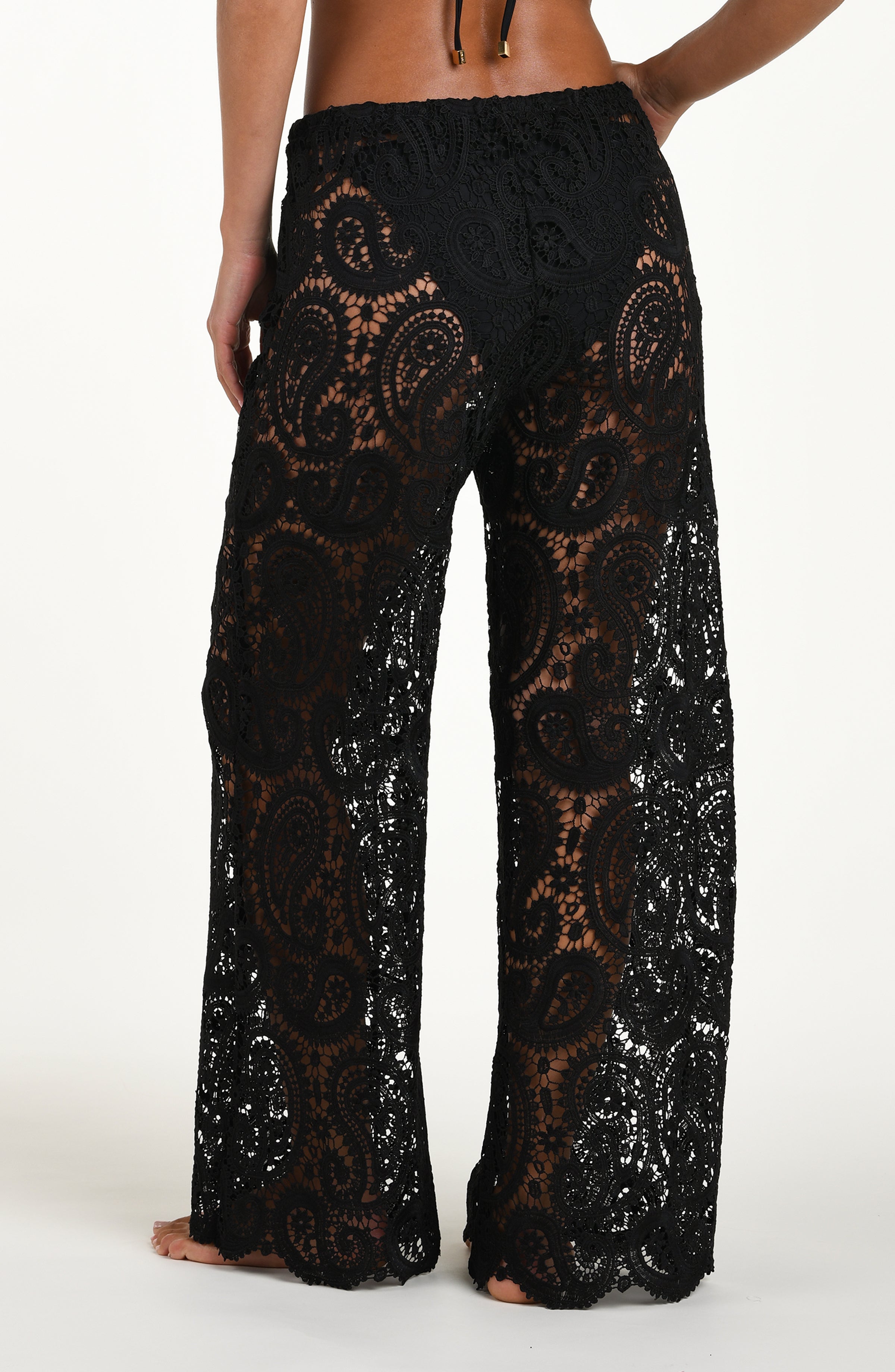 Black lace pants worn by a person on a white background