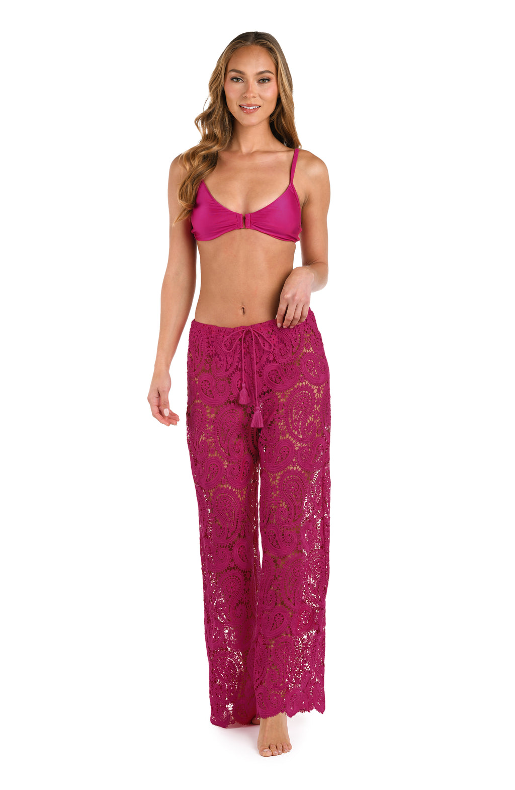 A person wearing bright fuchsia lace wide-leg pants with a drawstring waist  and matching bikini top against a white background.