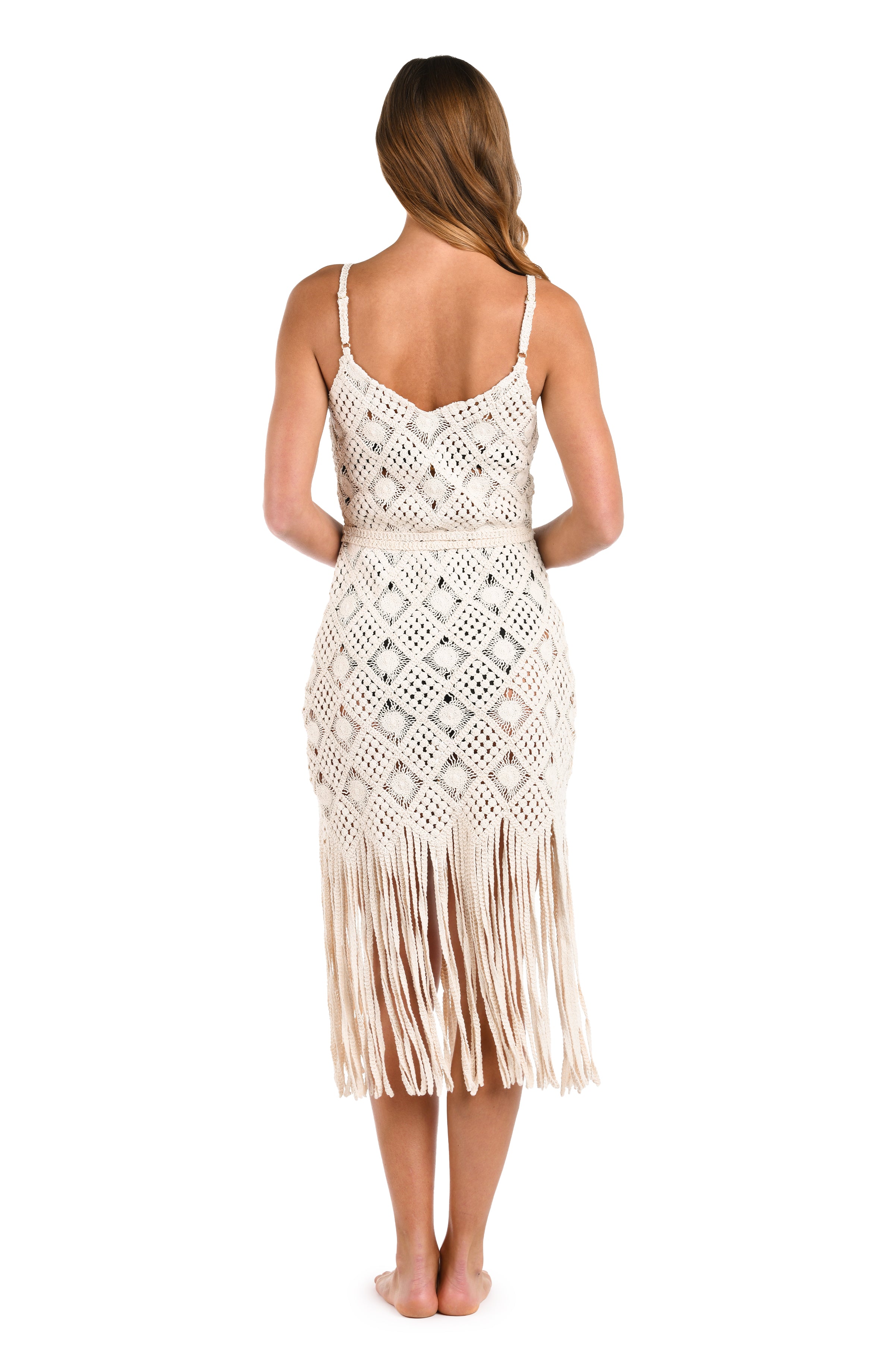 Woman wearing an ivory crochet dress against a white background. 