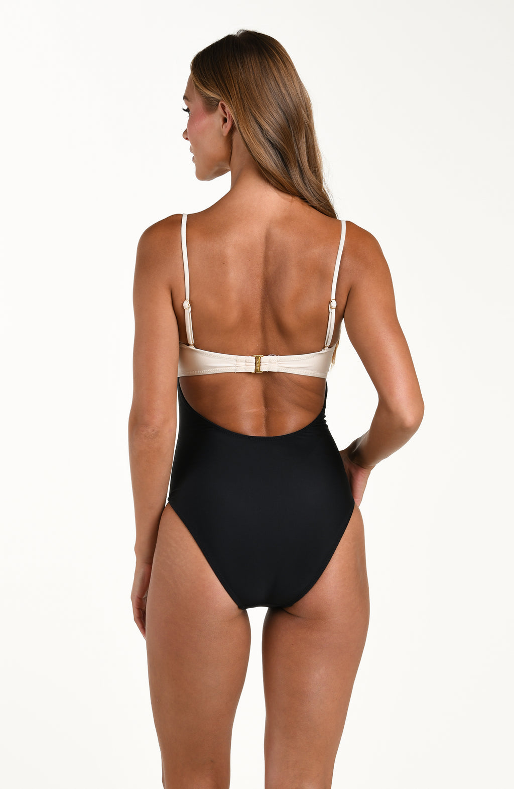 Woman wearing a black and white one piece swimsuit against a white background.