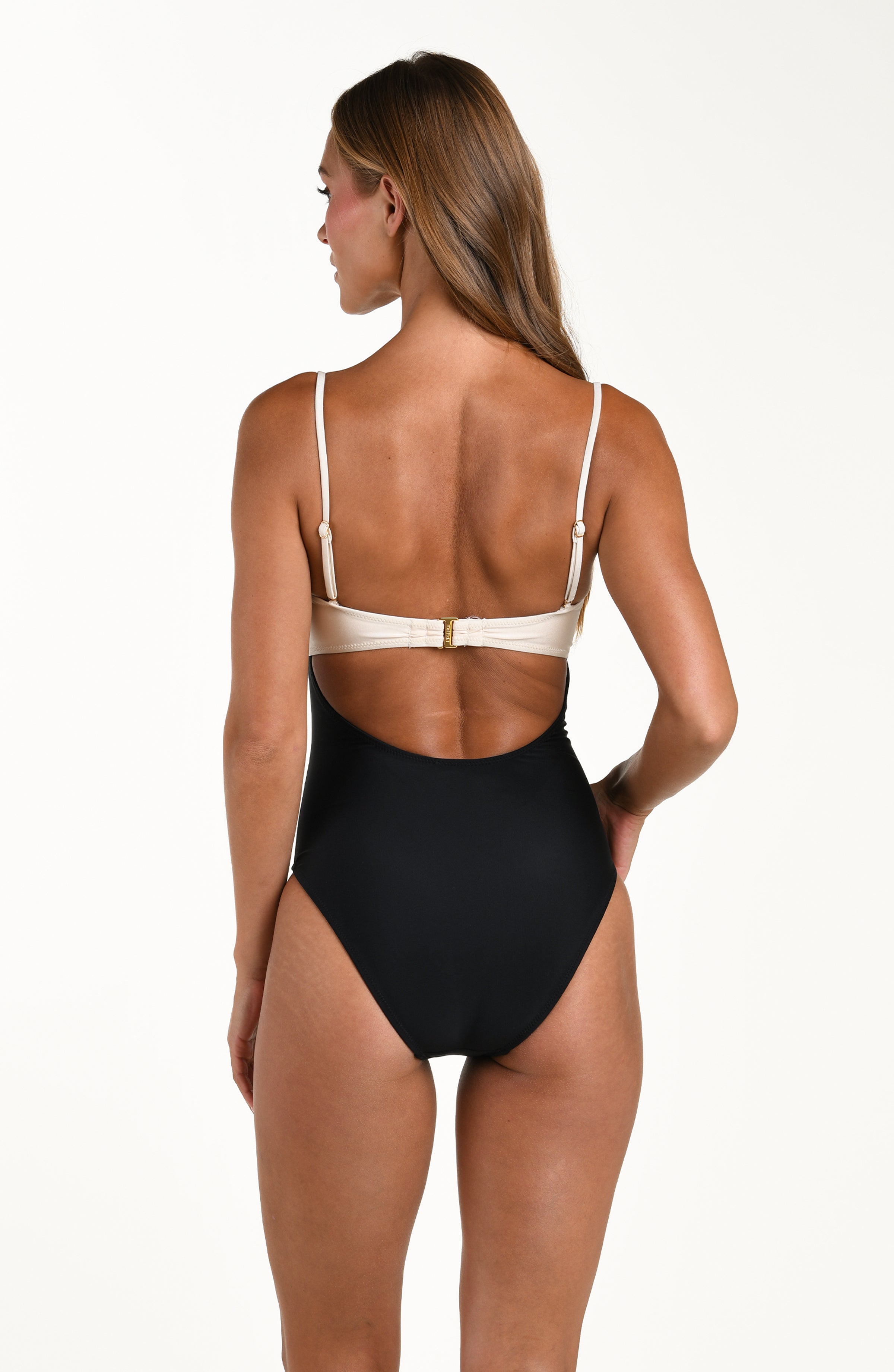 Woman wearing a black and white one piece swimsuit against a white background.