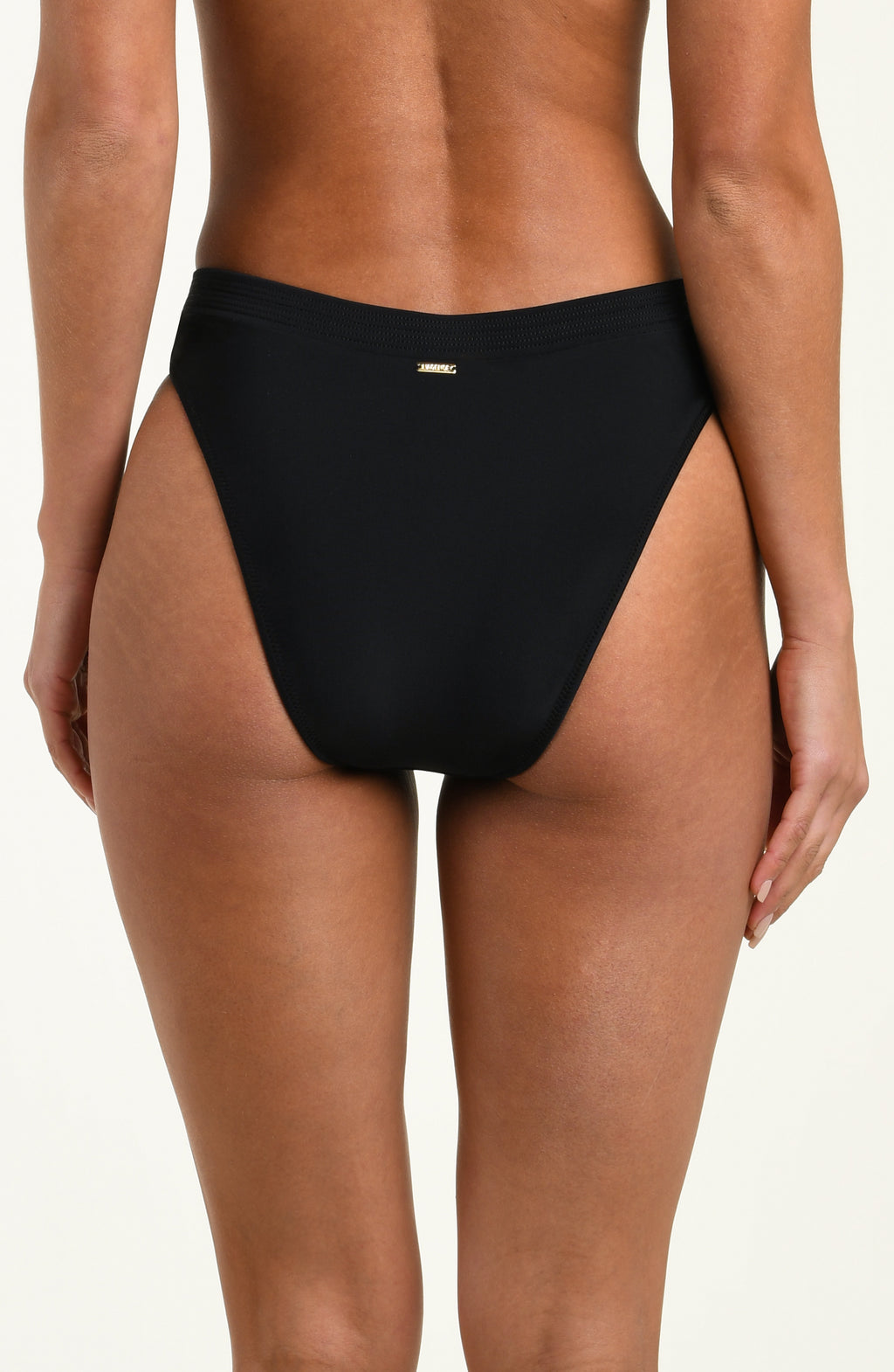 Black bikini bottom worn by a person on a white background