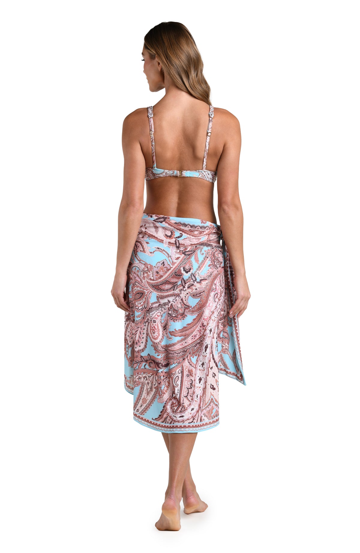 Woman wearing a multicolored sarong cover up and a matching bikini top against a white background.