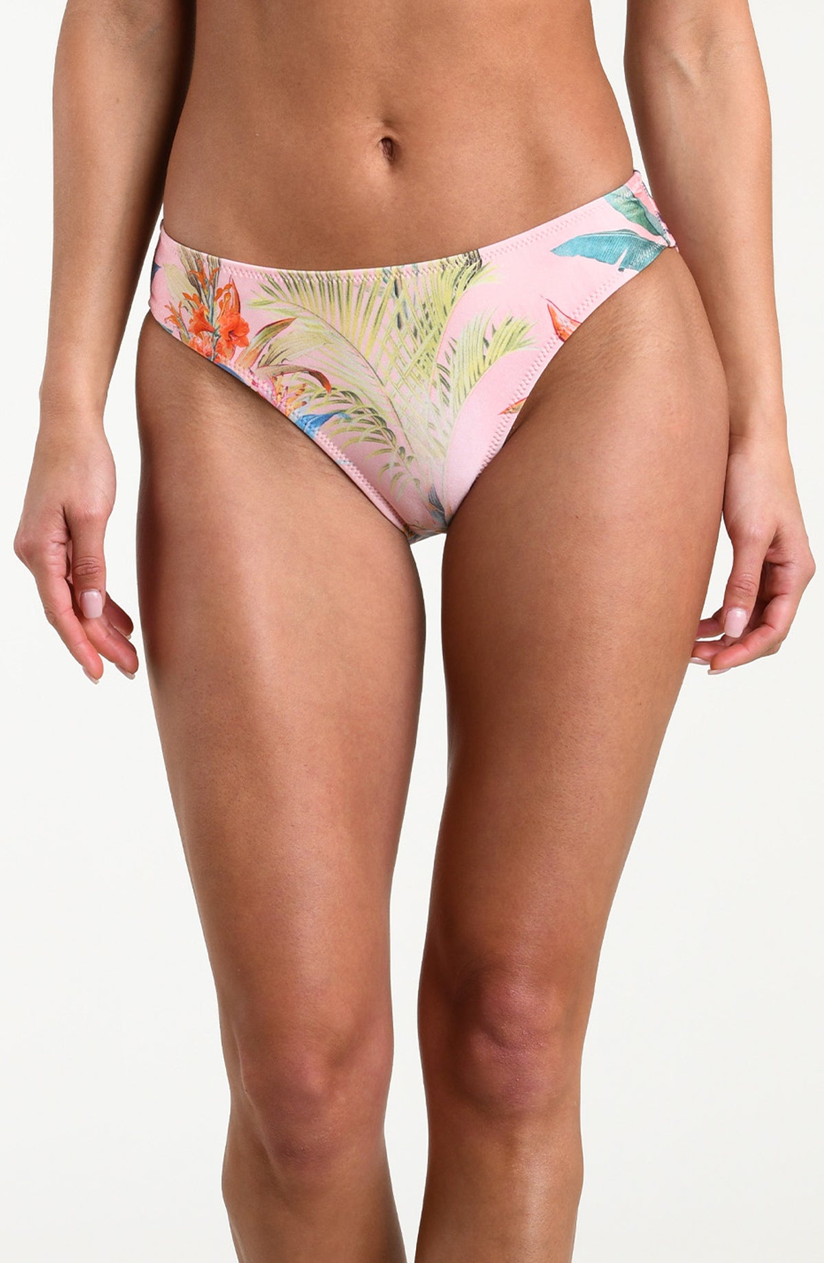 Woman wearing a multicolored tropical printed bikini bottom against a white background. 