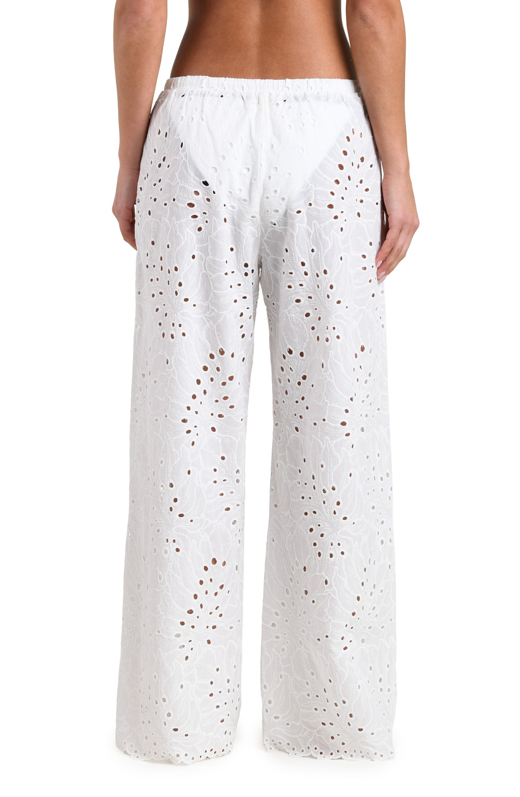 Woman wearing white cover up pants against a white background. 